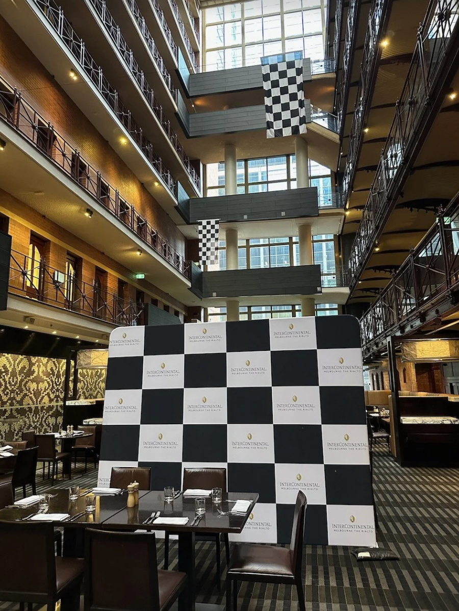 Interior of a restaurant or conference space at the InterContinental hotel, featuring a black and white checkered backdrop and a partially visible table set for dining.