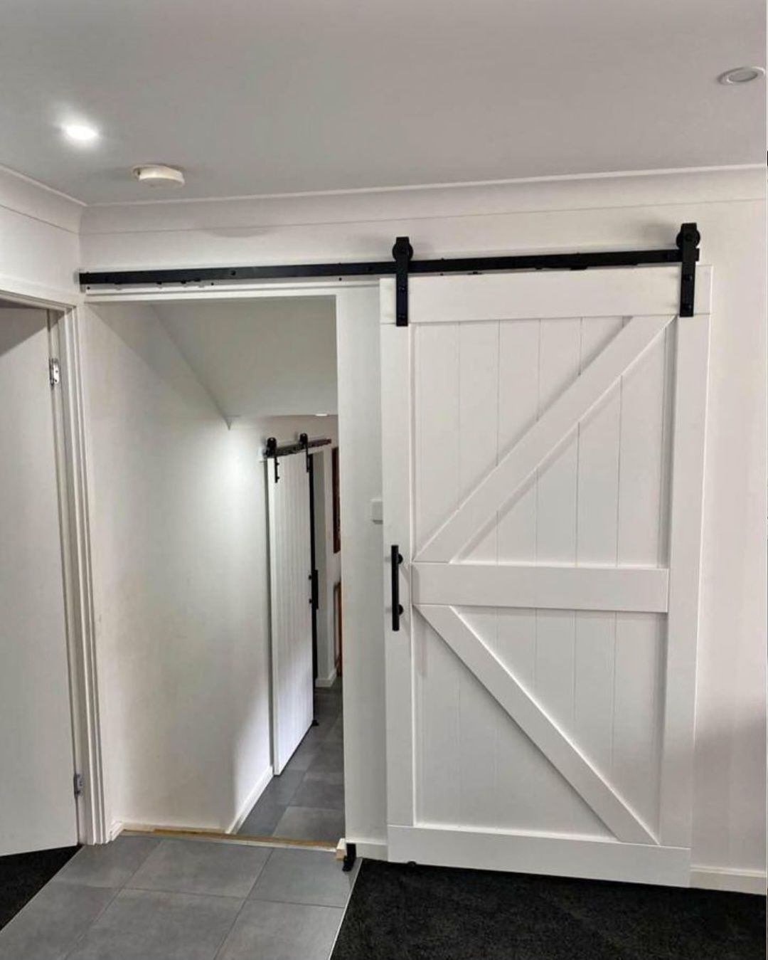 A white sliding barn door with black hardware in an indoor setting.
