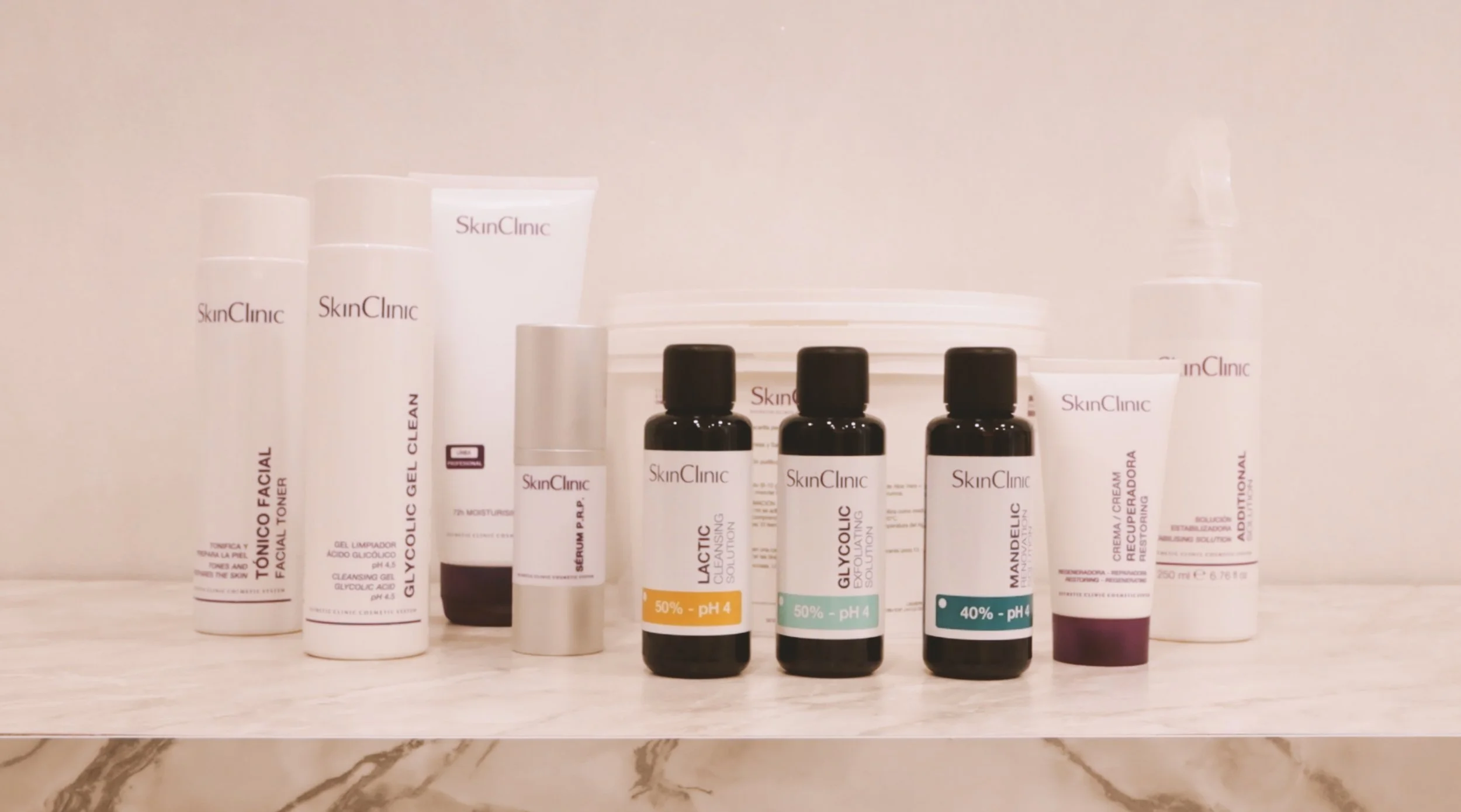 스킨케어 제품 여러 개가 진열된 모습, 대표 브랜드는 SkinClinic, 각 제품은 서로 다른 크기와 디자인, 일부는 검은 병과 흰 병으로 구분됨.