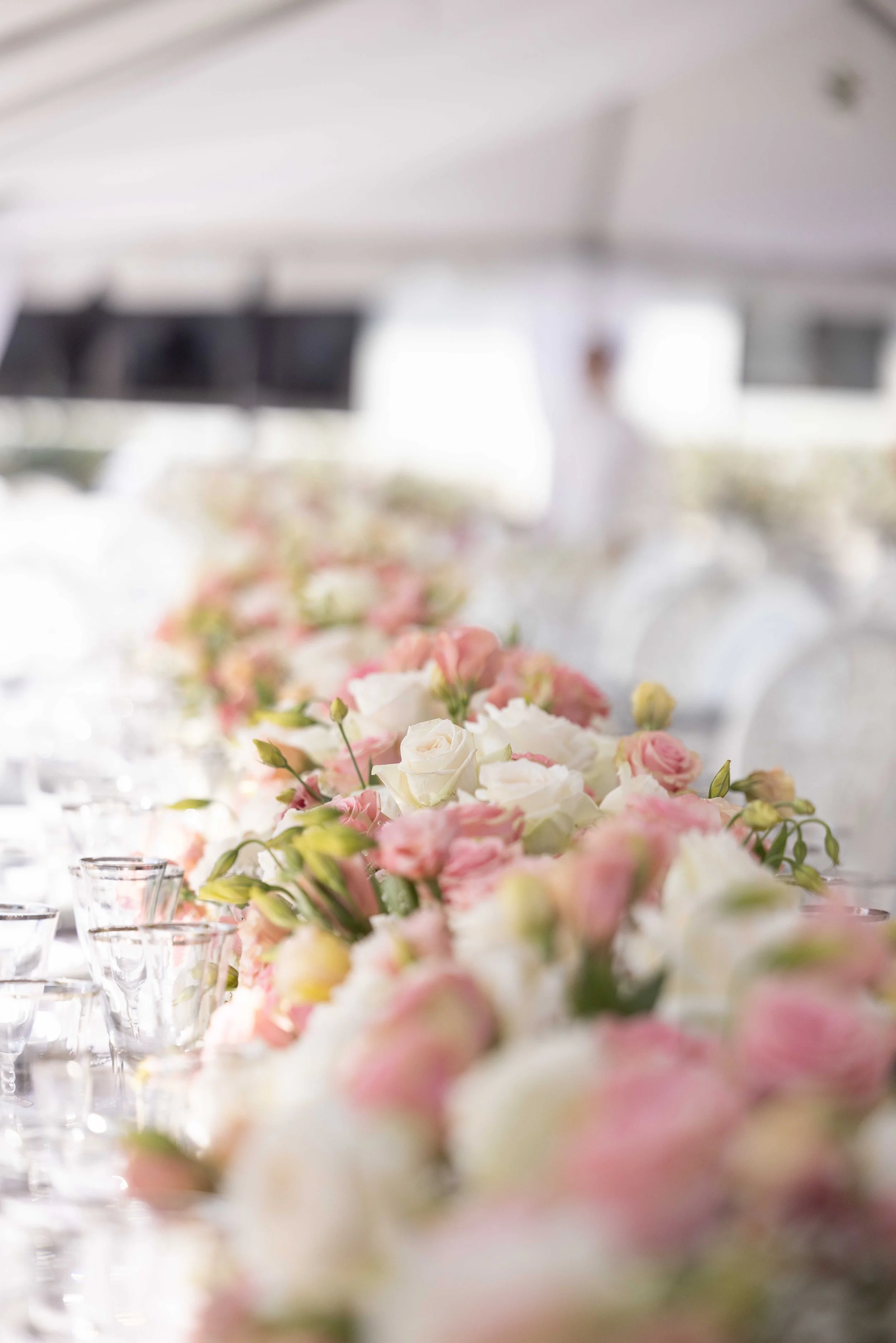 A table with a large floral centerpiece made of white and pink flowers during a daytime event.