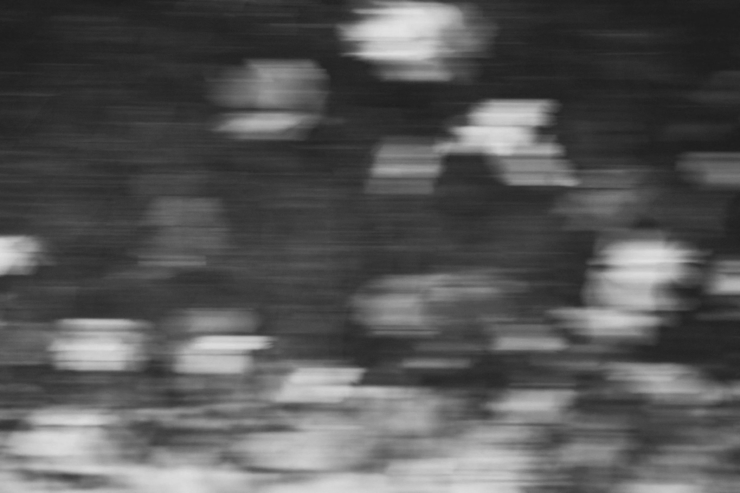 Image en noir et blanc montrant une scène floue avec des lignes horizontales et des formes indistinctes, évoquant un mouvement rapide ou une image abstraite.