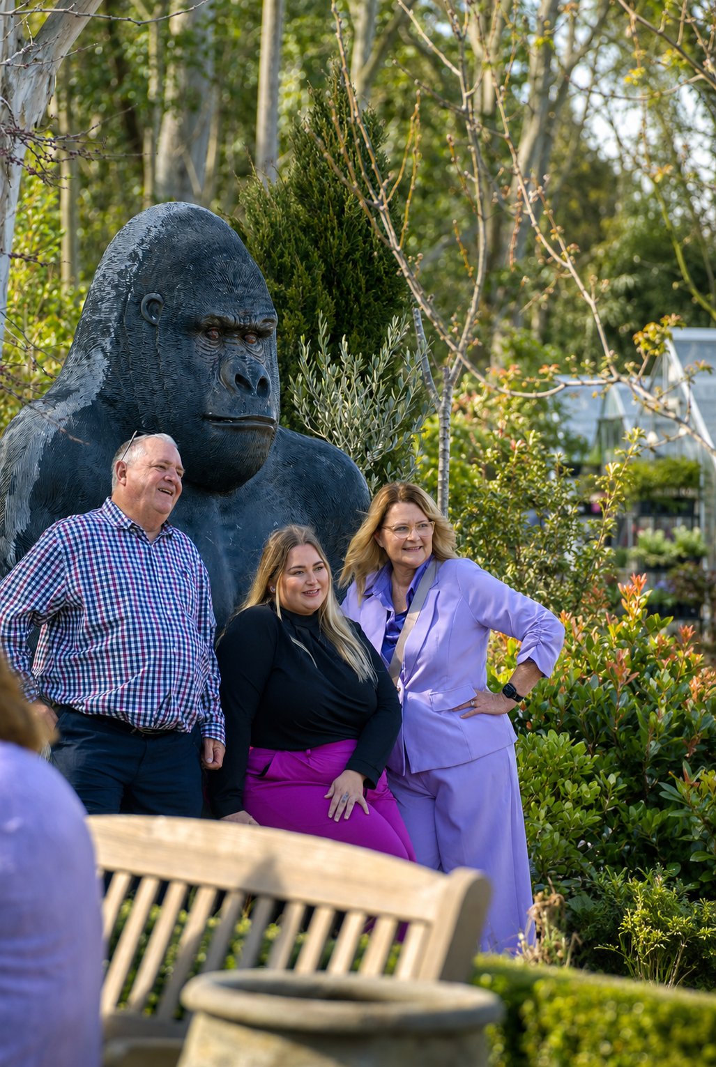 Four people standing in front of a large gorilla statue in a garden, smiling and posing for a photo.