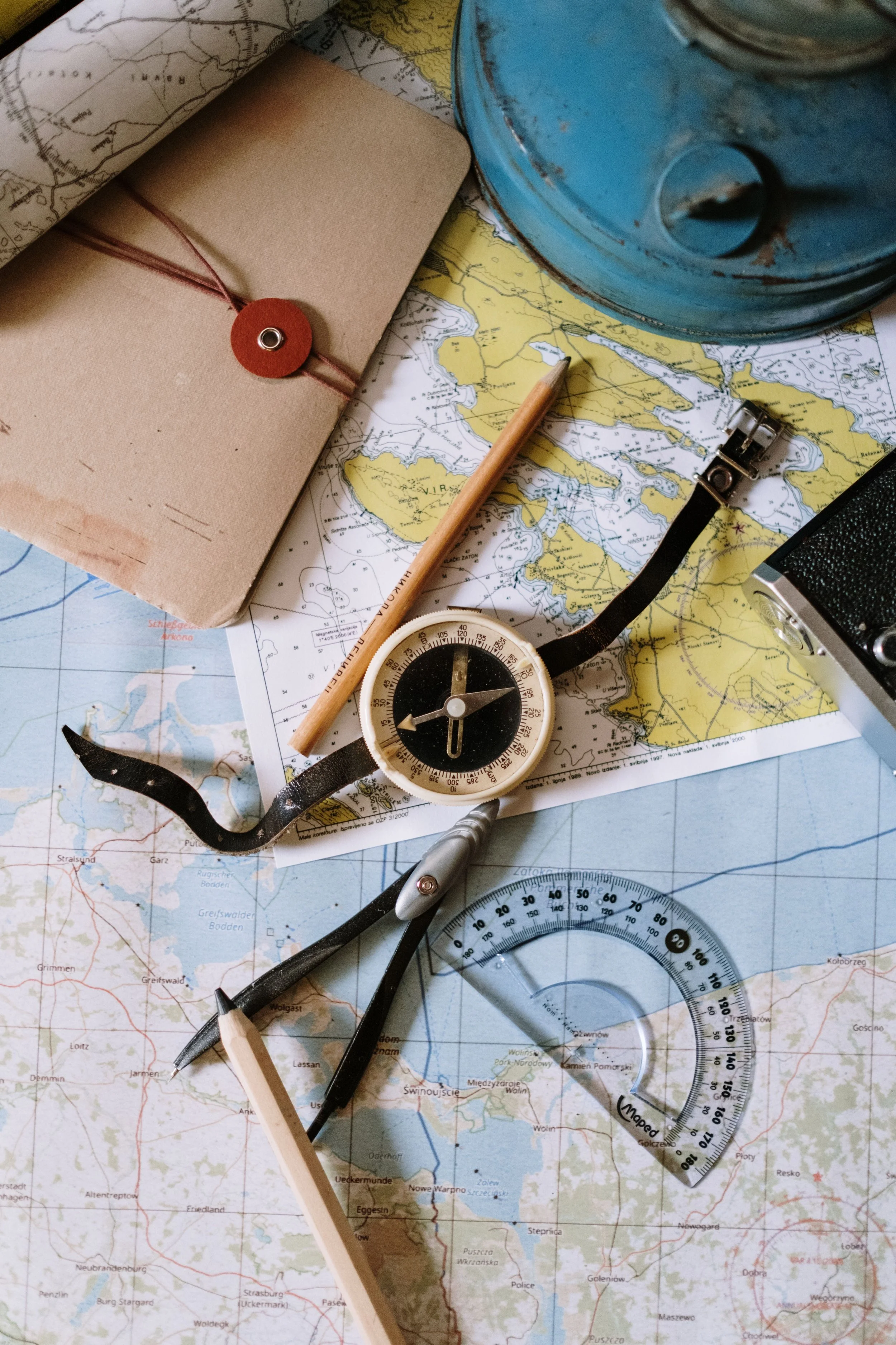 A compass, maps, notebook, and navigation tools arranged on a tabletop symbolize planning and adventure for family fundraising events that help send more children to summer camp.