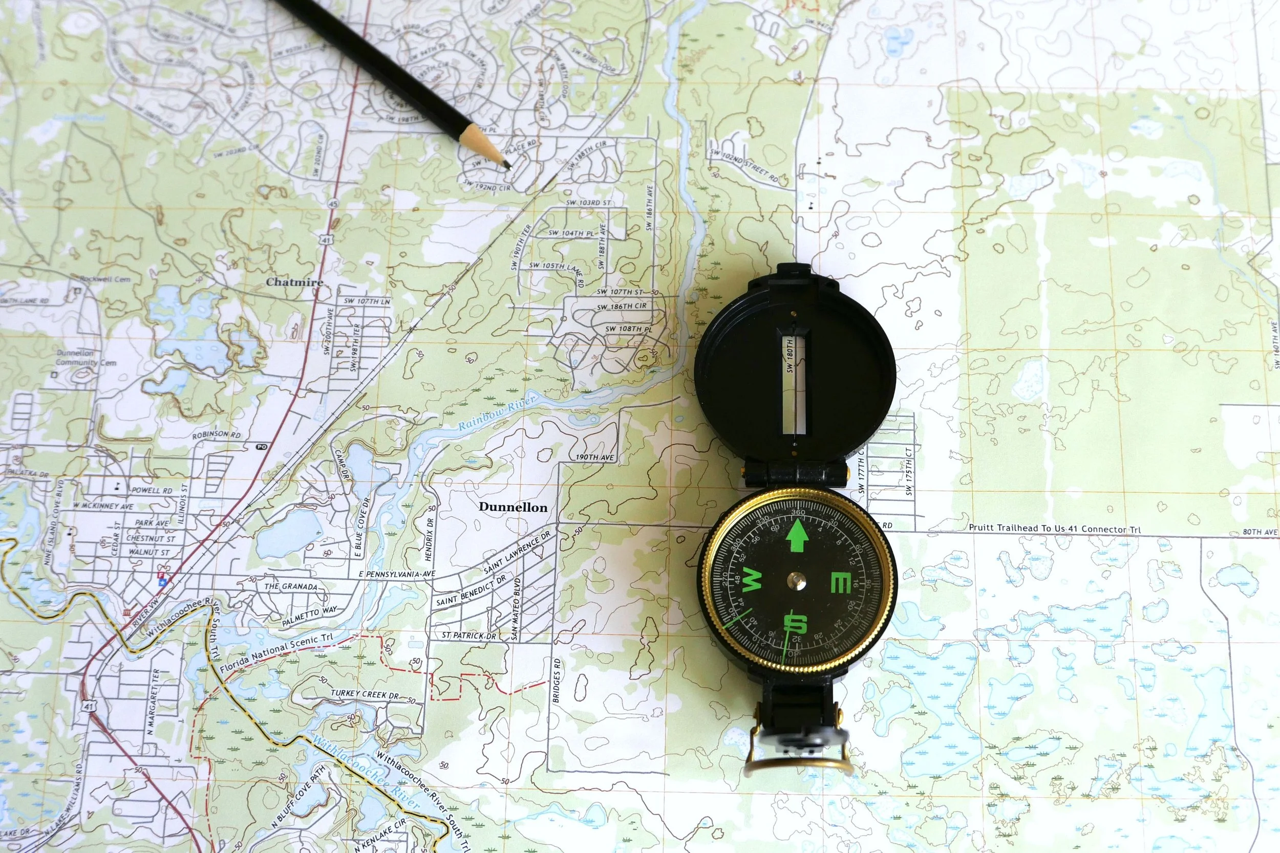 An open compass positioned on a trail map symbolizes navigation training offered through scholarships for summer programs for high school students focused on outdoor skills and exploration.