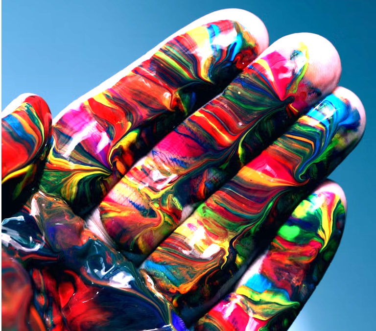 Close-up of fingers covered in multicolored marbled paint against a light blue background.