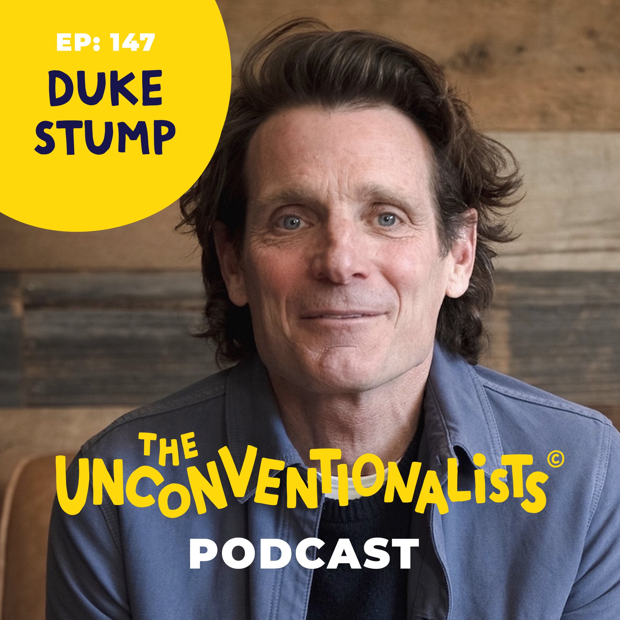 A close-up photo of a man with grayish hair and blue eyes wearing a dark jacket and a blue shirt, with a blurred wooden background. There is a yellow graphic overlay with bold text stating 'EP: 147 DUKE STUMP THE UNCONVENTIONALIST PODCAST'.