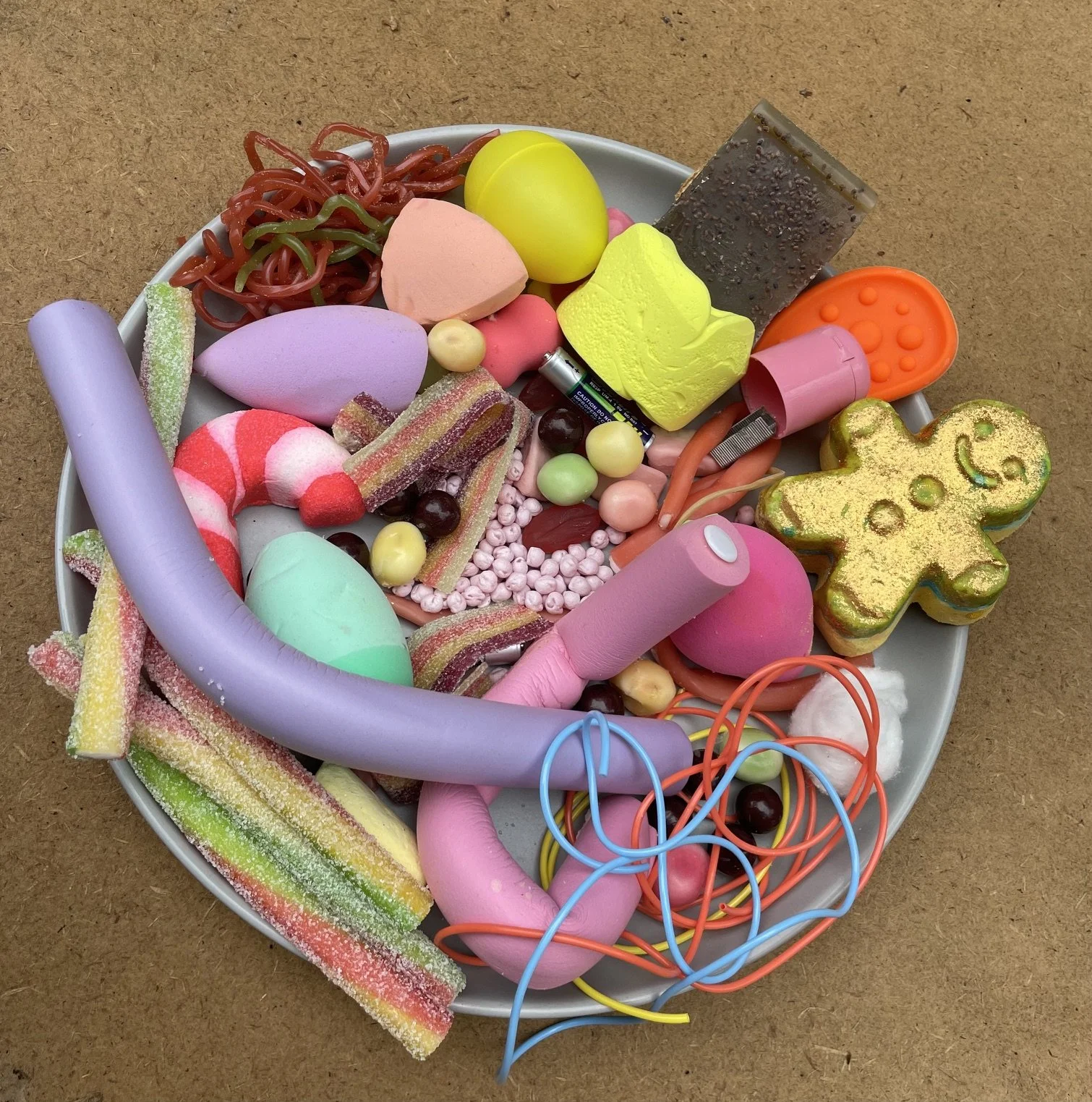 Plate containing mixed edible and non‑edible items resembling sweets, illustrating pica and polydipsia risk.