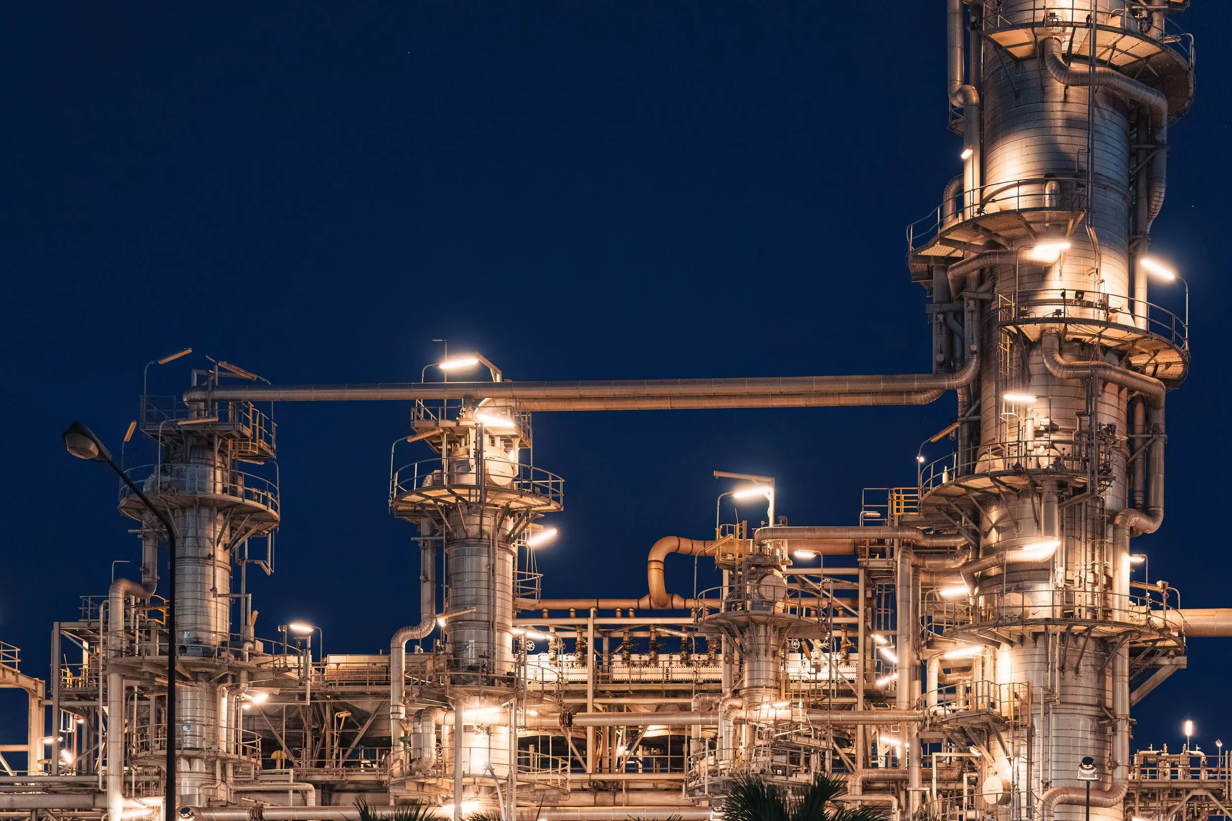 An industrial plant with multiple large metal pipes and towers illuminated at night.