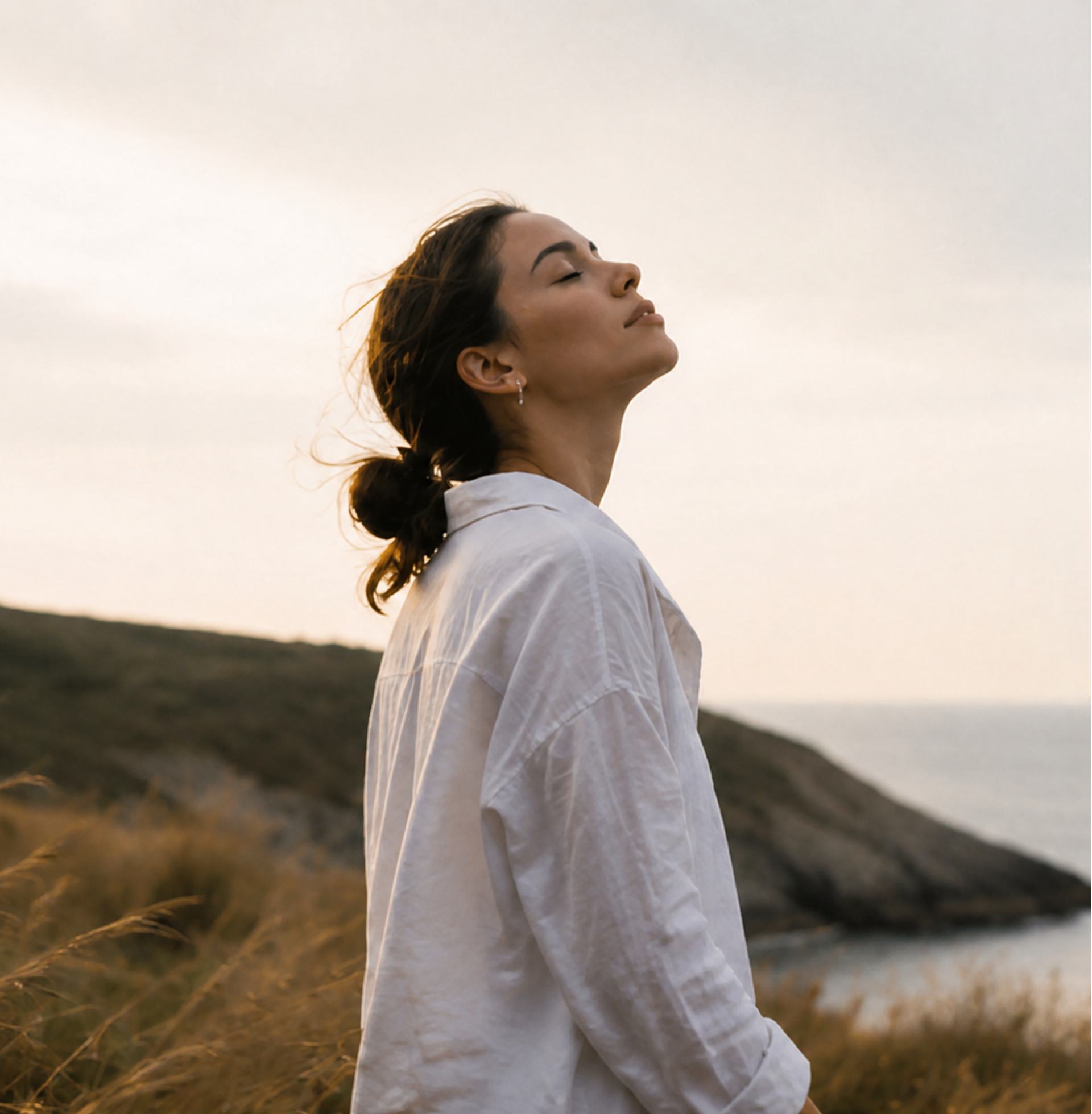 Woman relaxing with closed eyes by the coast, representing calm through hypnotherapy in Dubai