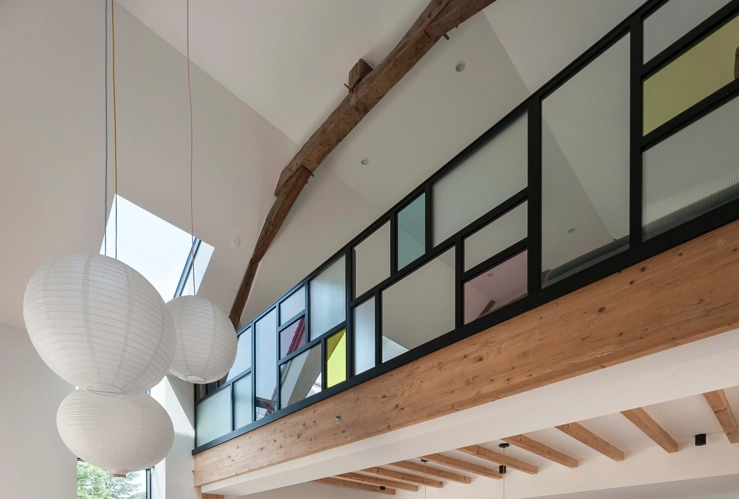 Un intérieur moderne d'une maison avec un salon et une cuisine, grande pièce lumineuse avec fenêtres, meubles colorés, tapis et lampes suspendues en forme de boule.