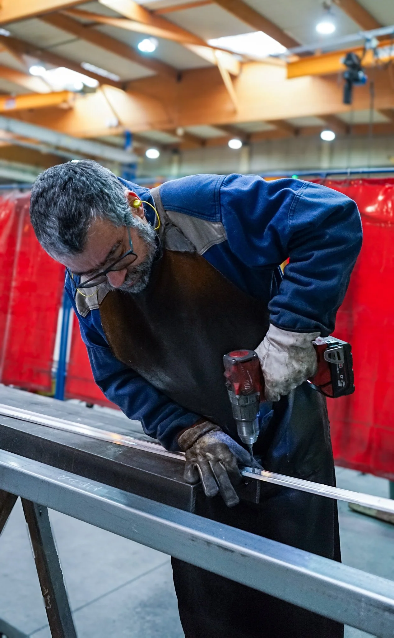 Un homme travaillant, portant des EPI, dans l'atelier de fabrication