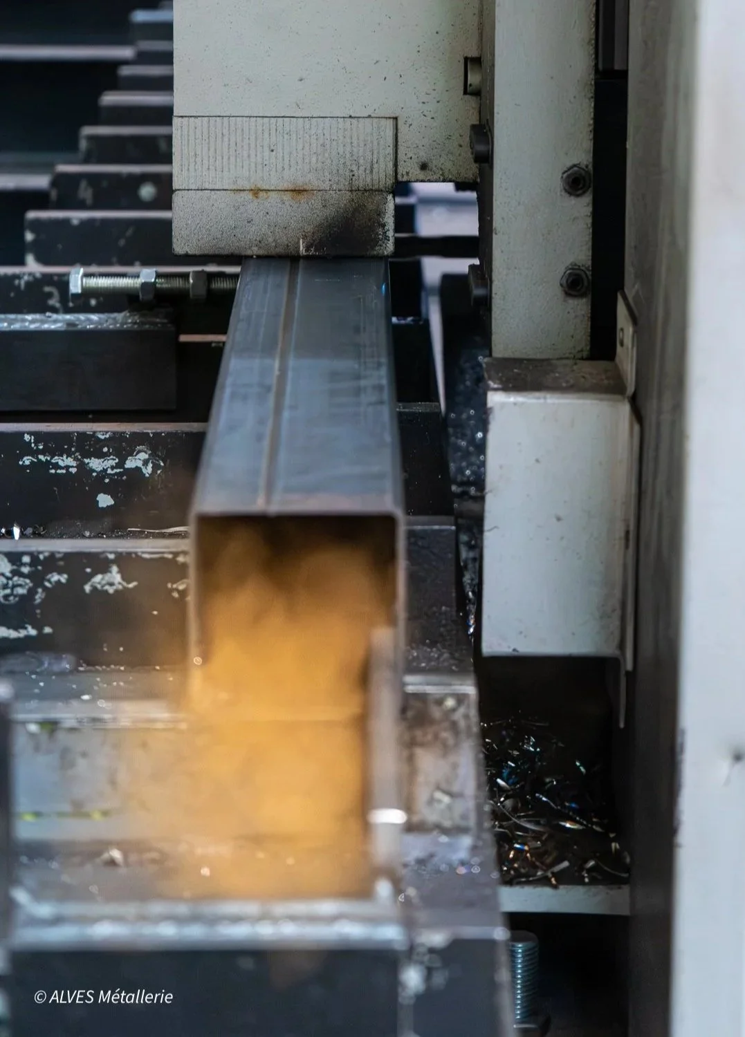 Une machine-outil de fabrication métallique, avec une pièce en acier rectangulaire en cours de traitement.