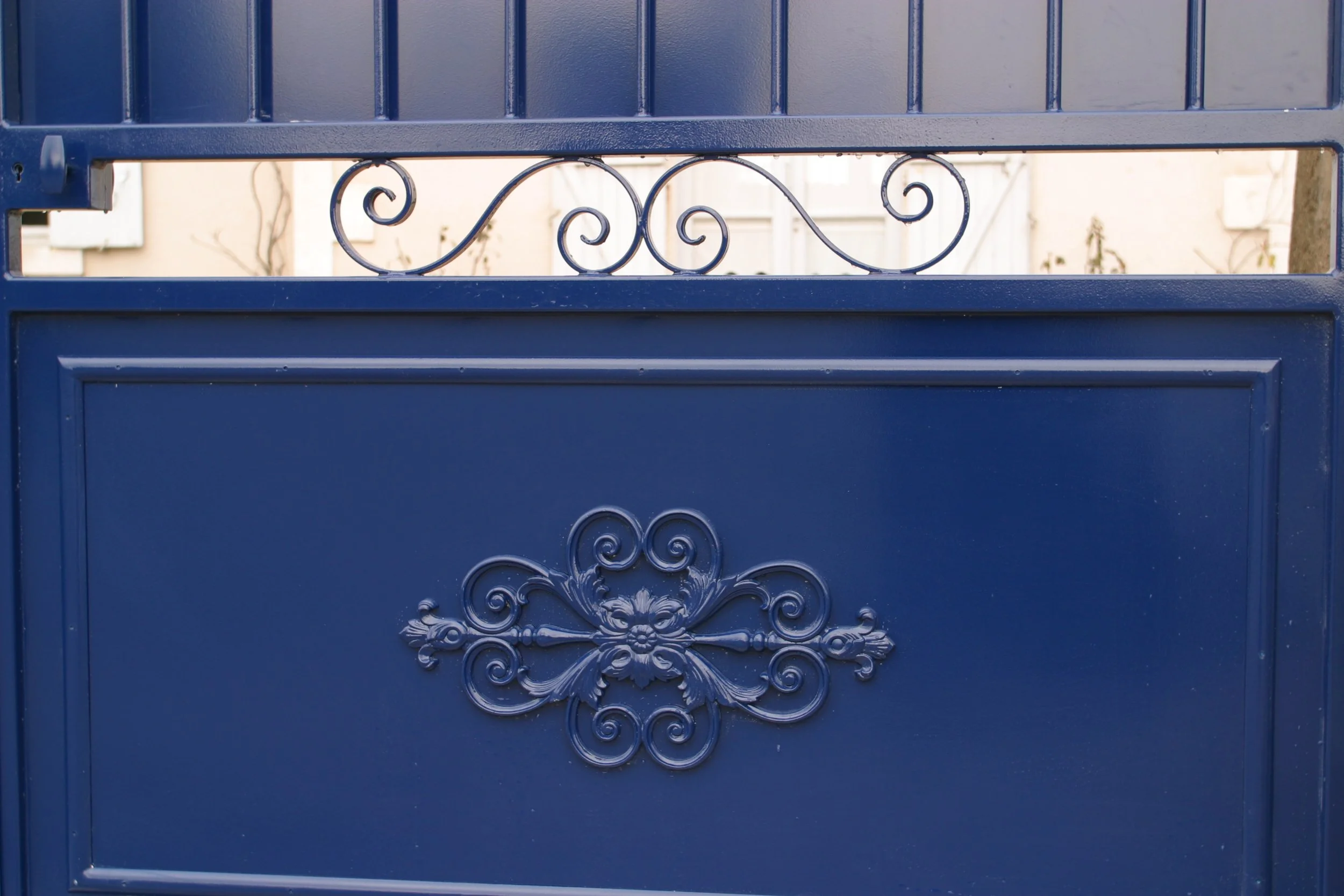 Grand portail en fer bleu avec des motifs décoratifs en spirale