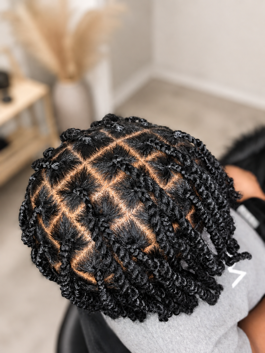 Top view of a person's head with neatly styled, glossy black micro twists.