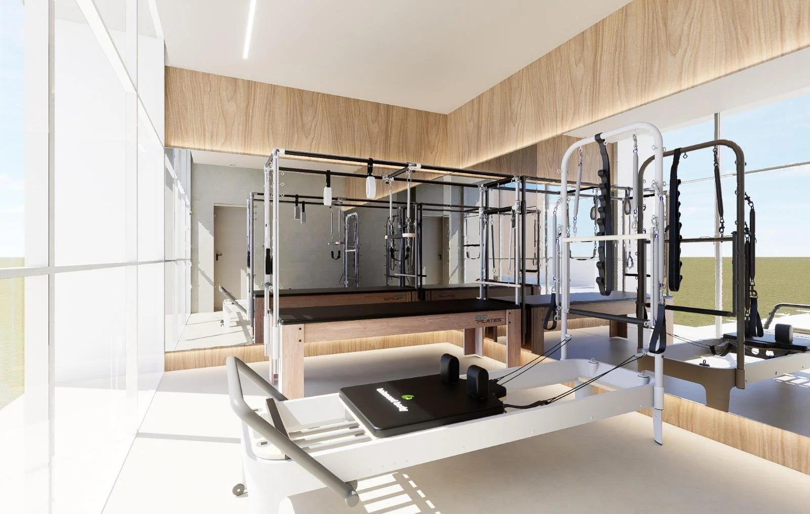 Sala de reabilitação com equipamentos de Pilates e barra fixadora ao fundo, iluminaçao natural e paredes de vidro.