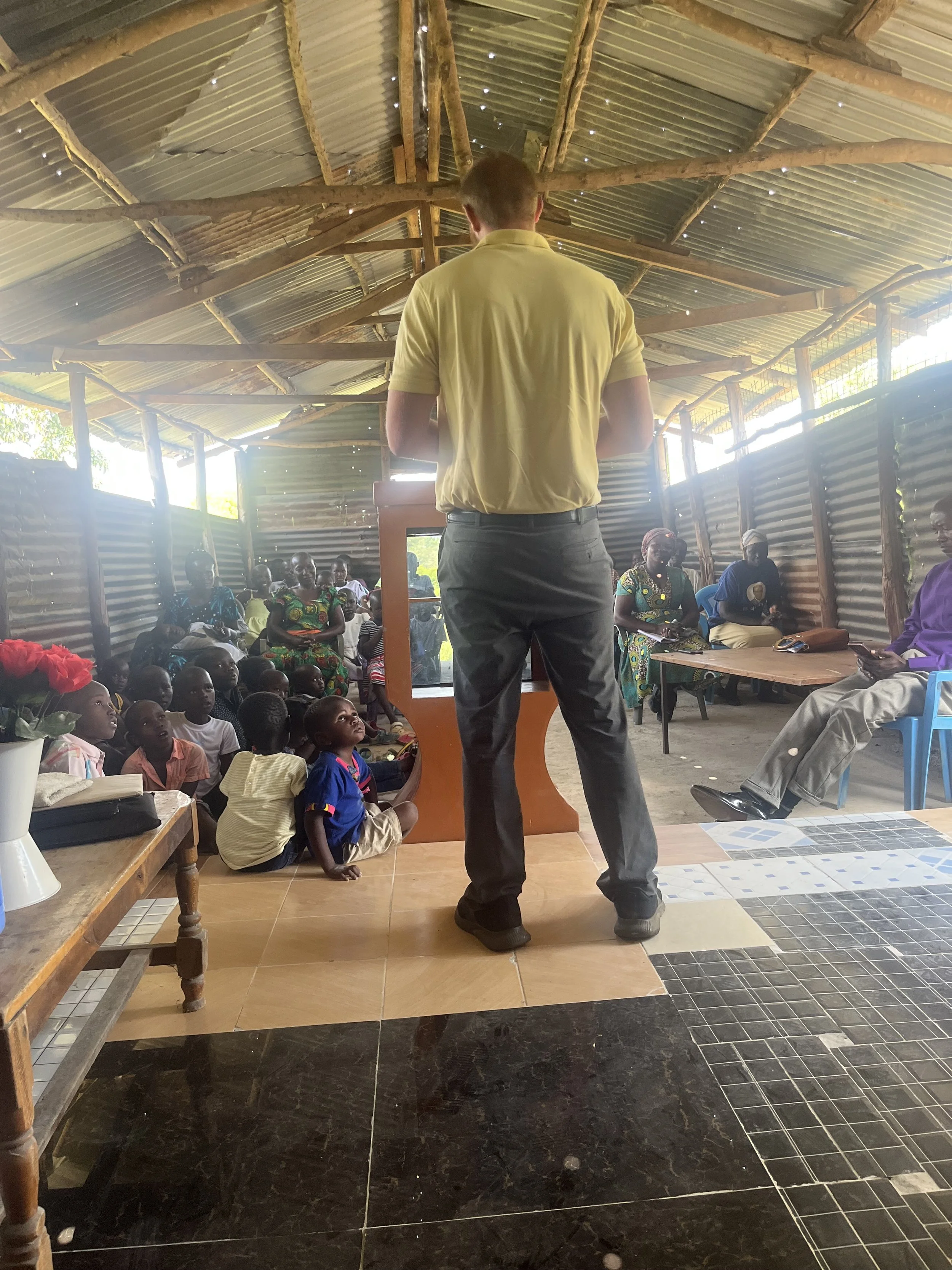 Brother Caleb Shuford bringing the word of God to widows, orphans and men of God gathered around in an orphanage during mission trip with Broken2Salvation Ministries in Kenya Africa Revival Baptist and Pentecostal 