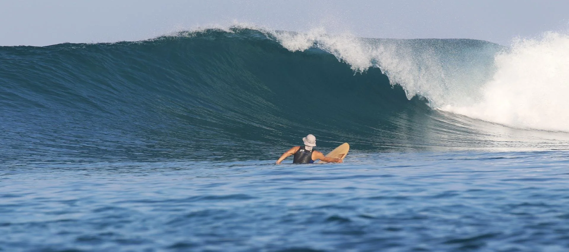 Surfer paddling toward a powerful wave at Suckies, Rote Island, Indonesia