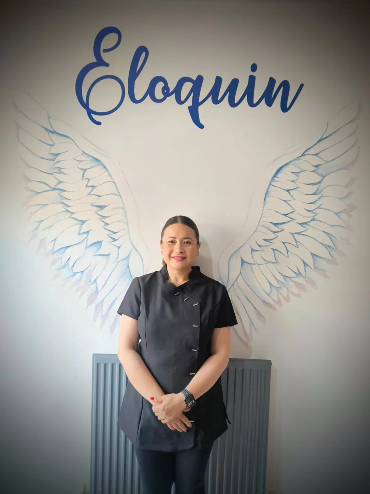 Woman standing in front of a wall with angel wings illustration and the text 'Eloquin' above.