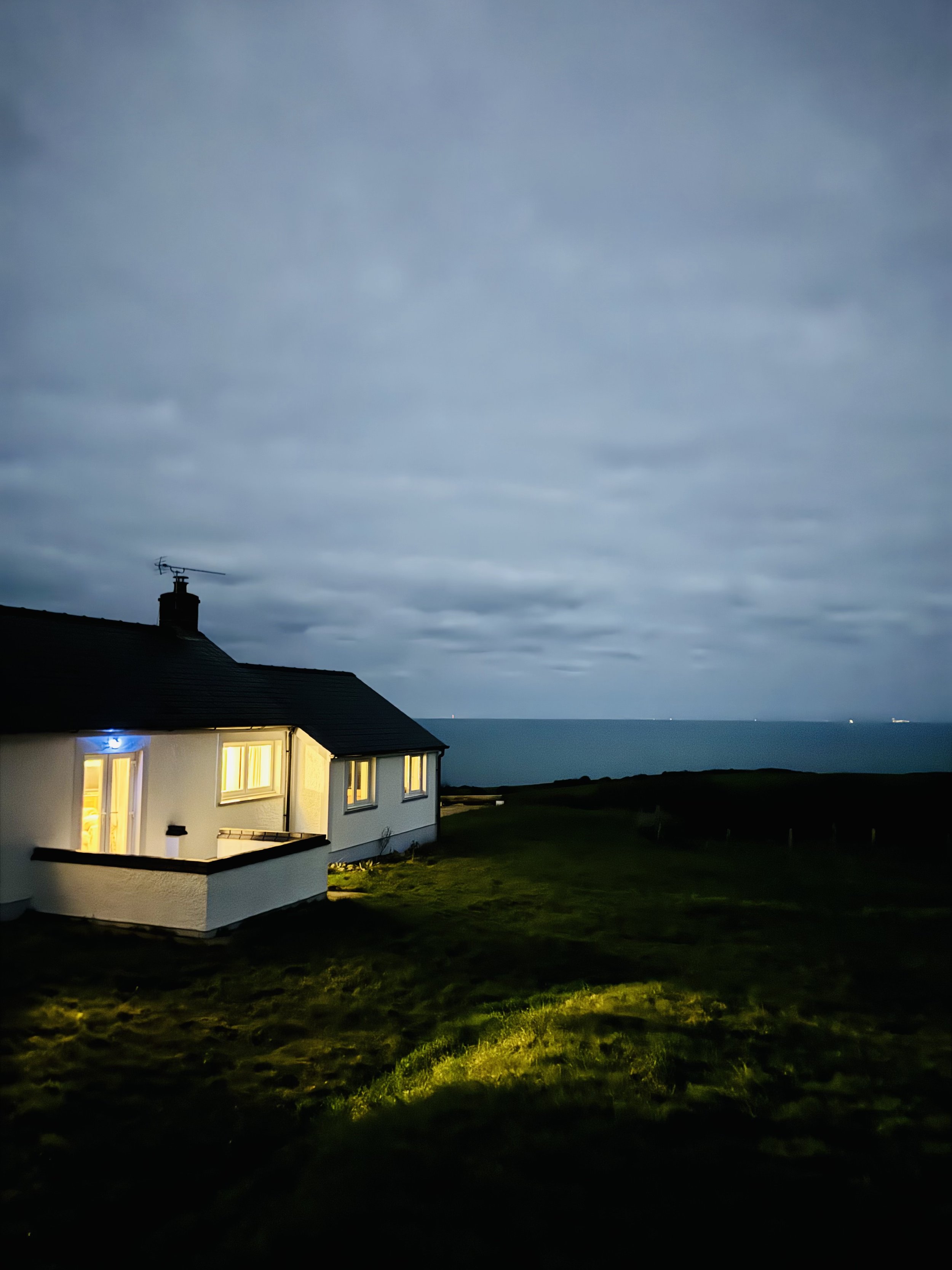 Y Llaethdy at night with the lights of Aberystwyth across the bay