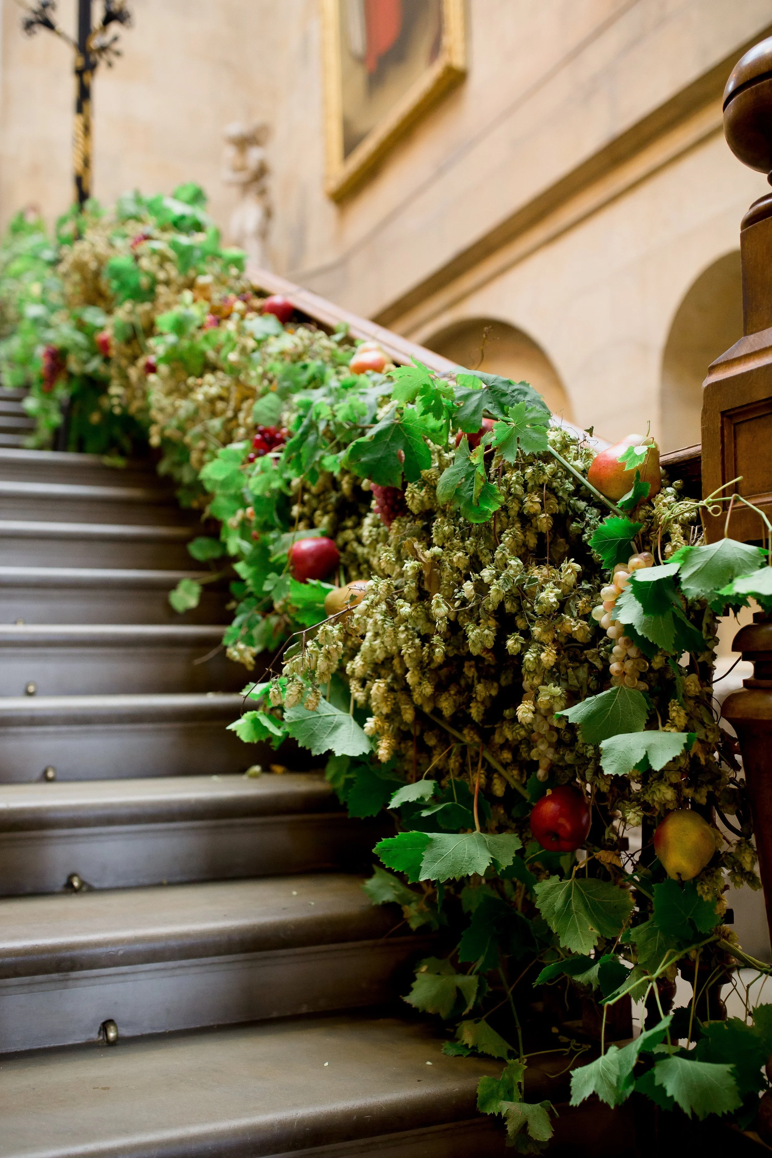 Decorated staircase with grapevine leaves, grapes, and apples as floral arrangement.