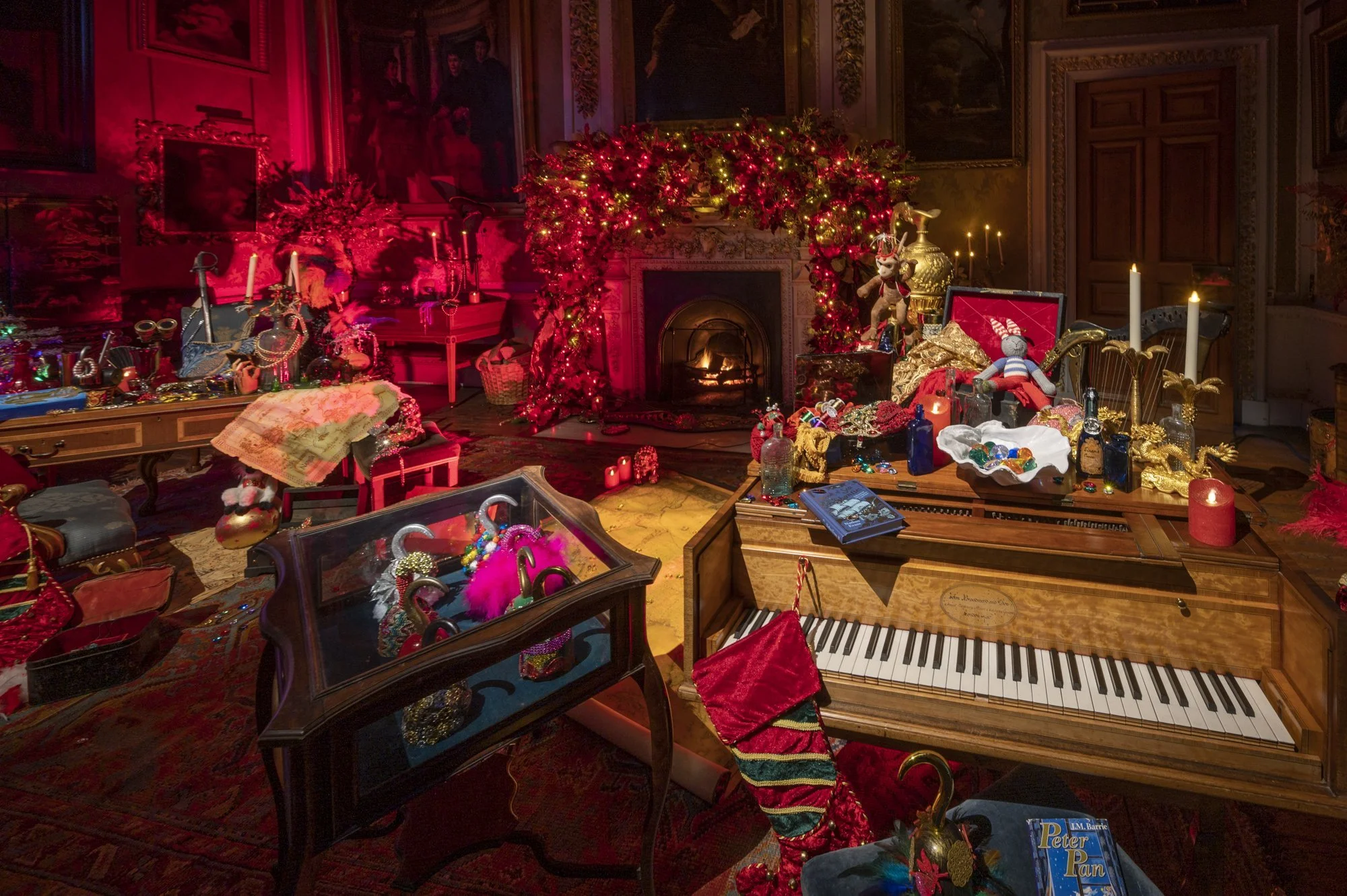 Decorative room with a fireplace, Christmas decorations, and a grand piano surrounded by various ornaments, toys, and holiday decorations.