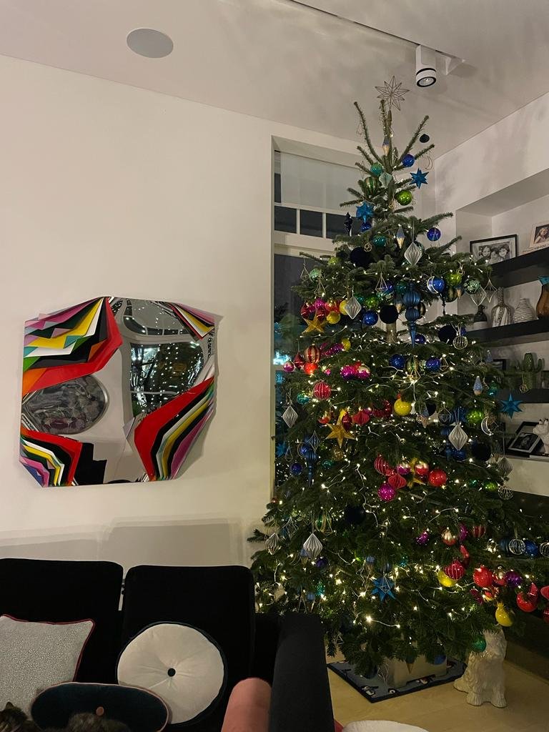 Decorated Christmas tree with colorful ornaments and lights in a living room.