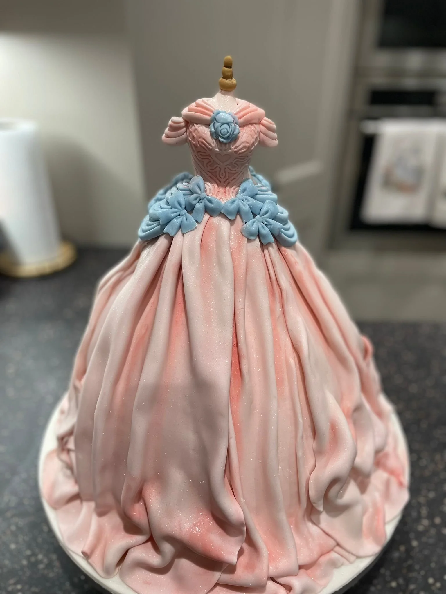 Decorative princess cake topper with pink and blue fondant, featuring a crown and intricate dress details.