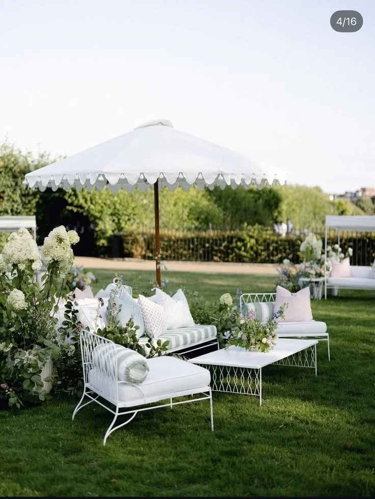 Person setting a dinner table with a wine glass, plates, a spoon, a fork, a small cup, a candle, and a flower in a vase.