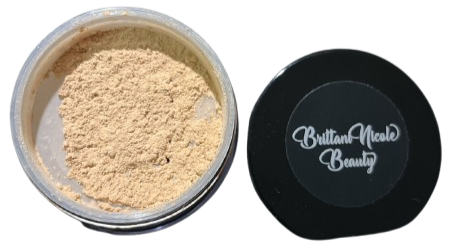 A container with a beige powder inside, next to a black lid with white script that reads 'Button & Meal Beauty'.