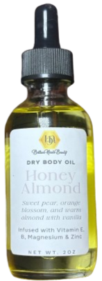 A small bottle of honey almond dry body oil with dropper cap, label indicating it contains Vitamin E, B, magnesium, vanilla, and is infused with sweet pear, orange blossom, and warm almond with vanilla scent.