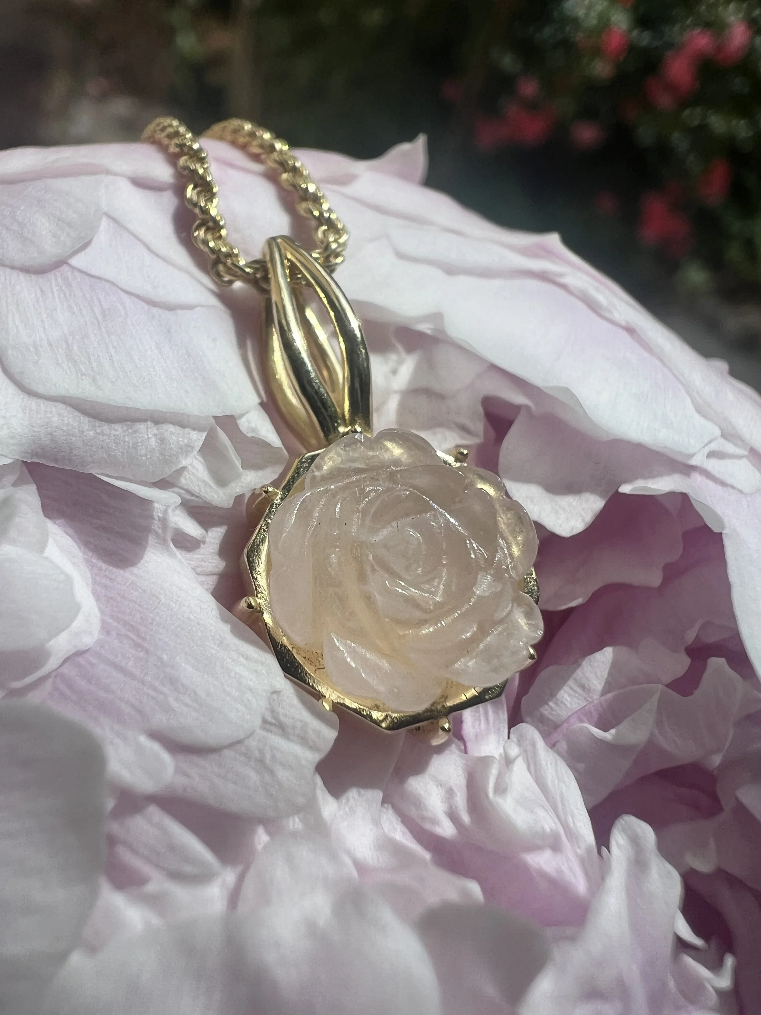 Goldene Kette mit einem Anhänger in Form einer Blume auf weißen Blütenblättern.
