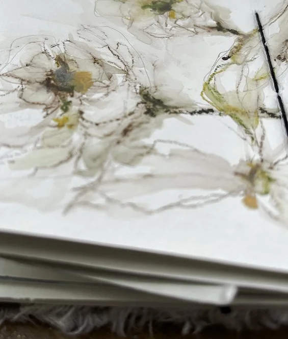 Open sketchbook with abstract watercolor painting featuring soft, flowing lines and muted colors including browns, yellows, and greens.