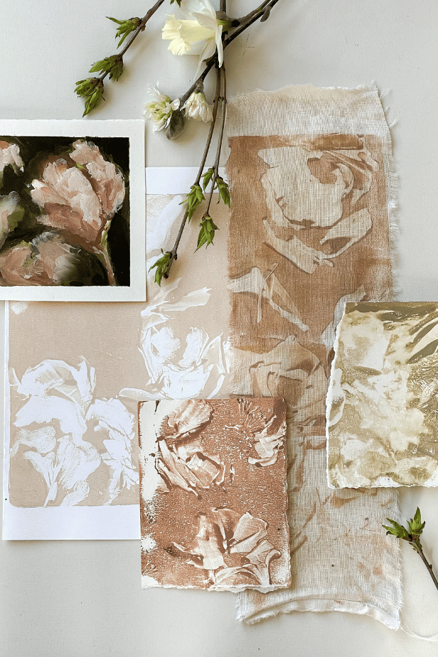 Various botanical art pieces and fabric swatches with floral engravings, decorated with white flowers and green branches on a light-colored background.