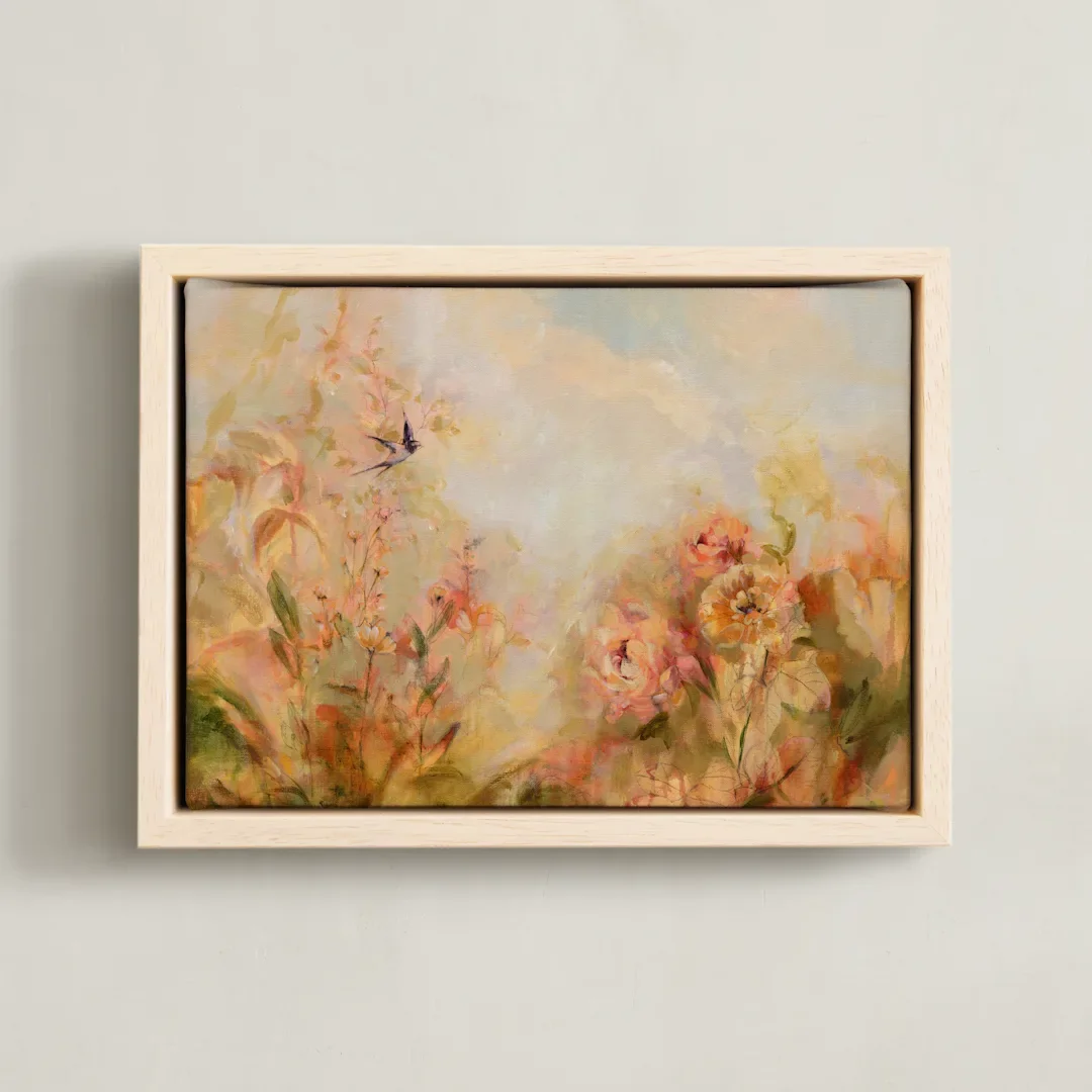 Watercolor painting of pink and orange flowers with a hummingbird flying nearby, framed and hung on a plain wall.