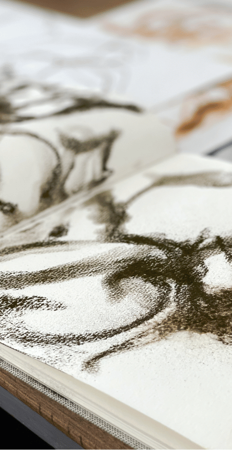 Close-up of an art sketch in progress, featuring a detailed partial portrait drawn with charcoal on paper.