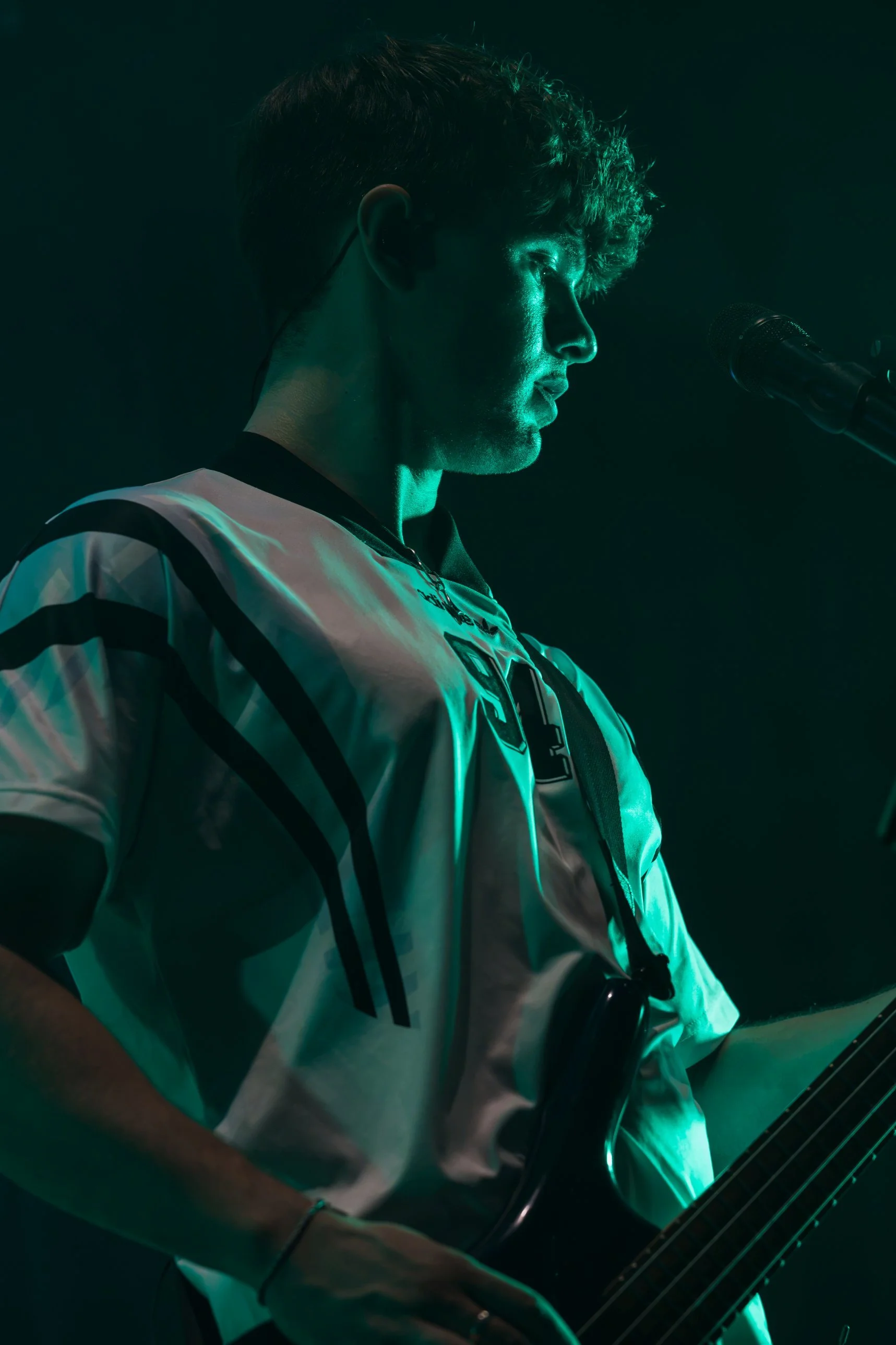 Bassist am Mikrofon im grünen Bühnenlicht, Profilaufnahme – Konzertfoto von der Kirchweih Gersthofen 2026