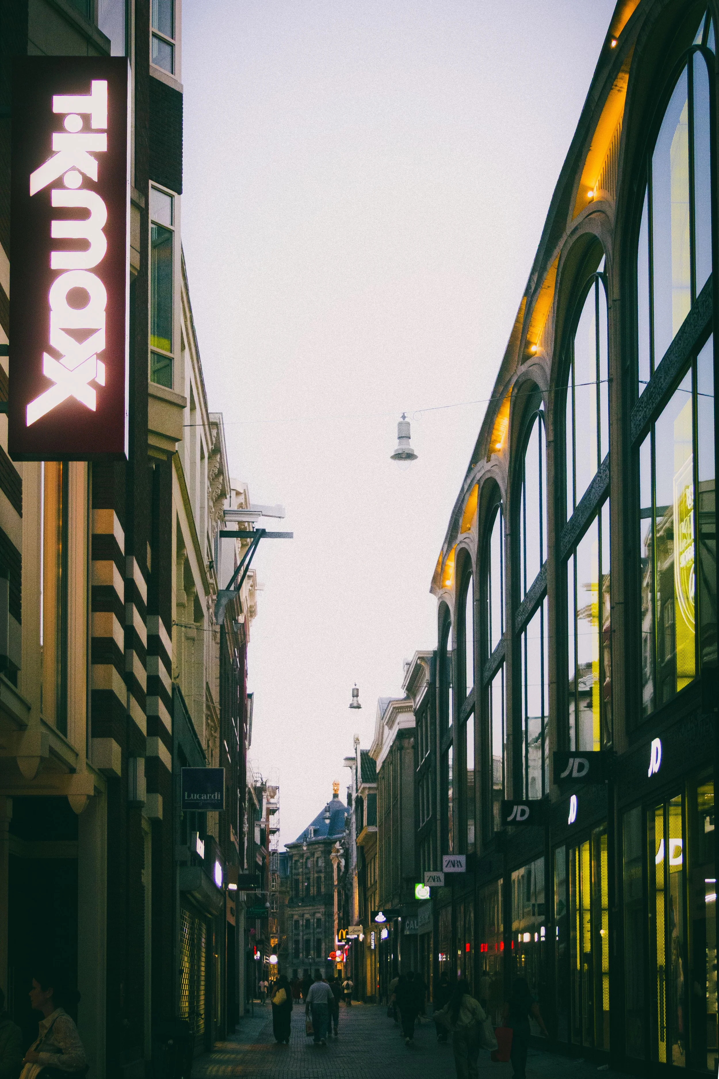 Enge Einkaufsstraße mit Geschäftsfassaden, im Vordergrund ein TK-Maxx-Schild