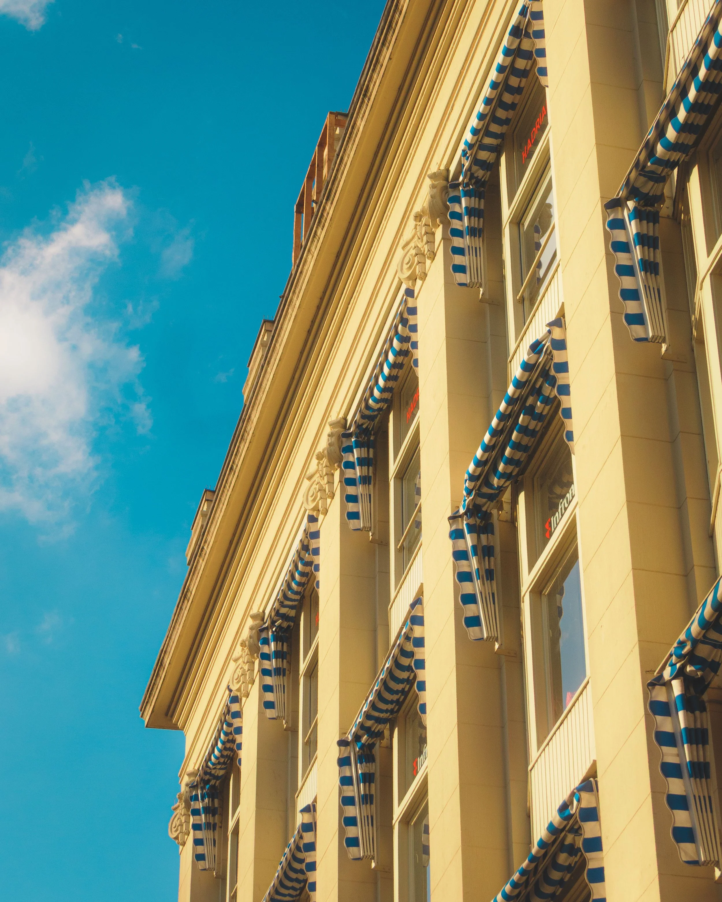 Historische gelbe Gebäudefassade mit verzierten Fensterläden vor strahlend blauem Himmel