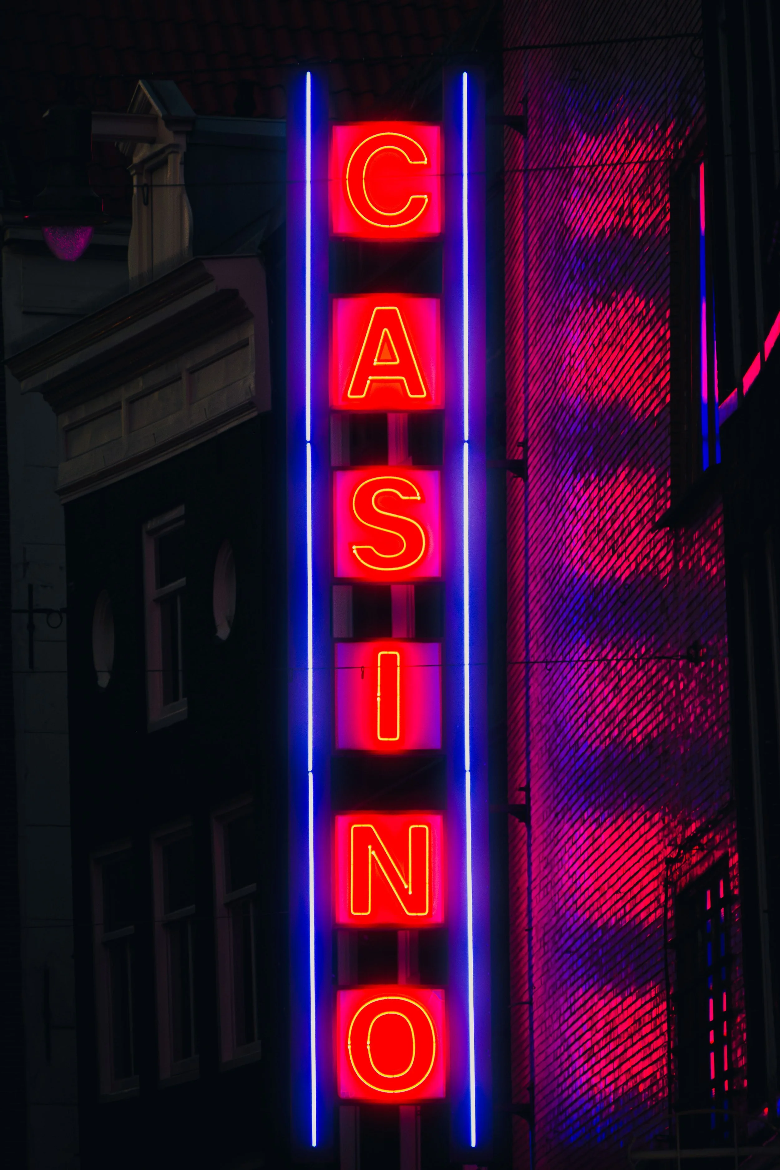 Vertikale Neonreklame mit dem Schriftzug "Casino" in leuchtendem Rot und Violett bei Nacht