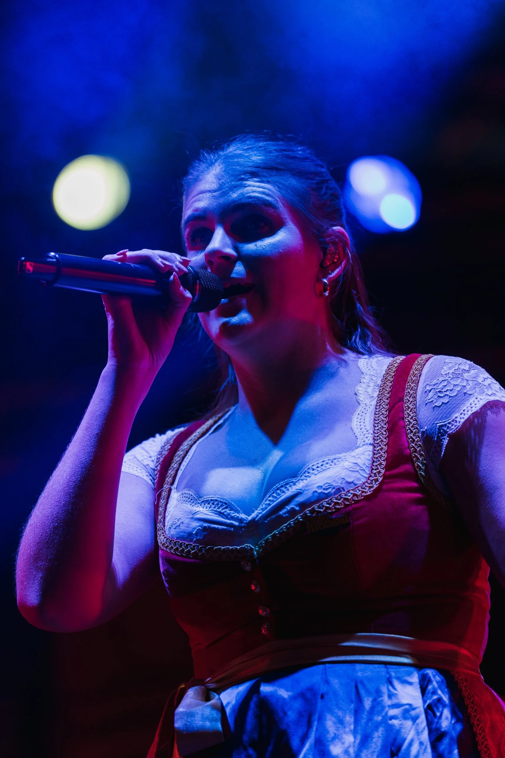Sängerin von Leck O'Mio im Dirndl am Mikrofon, blaues Bühnenlicht – Konzertfotografie Kirchweih Gersthofen 2026