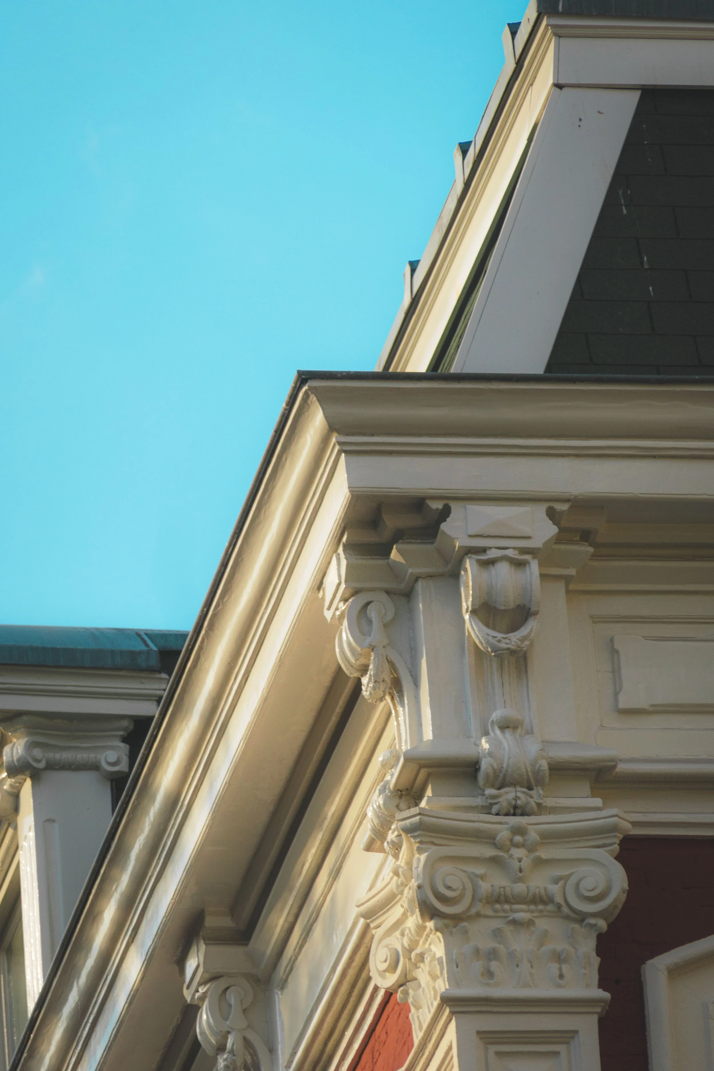 Detailaufnahme kunstvoller Steinornamente an einer Gebäudeecke vor türkisfarbenem Himmel