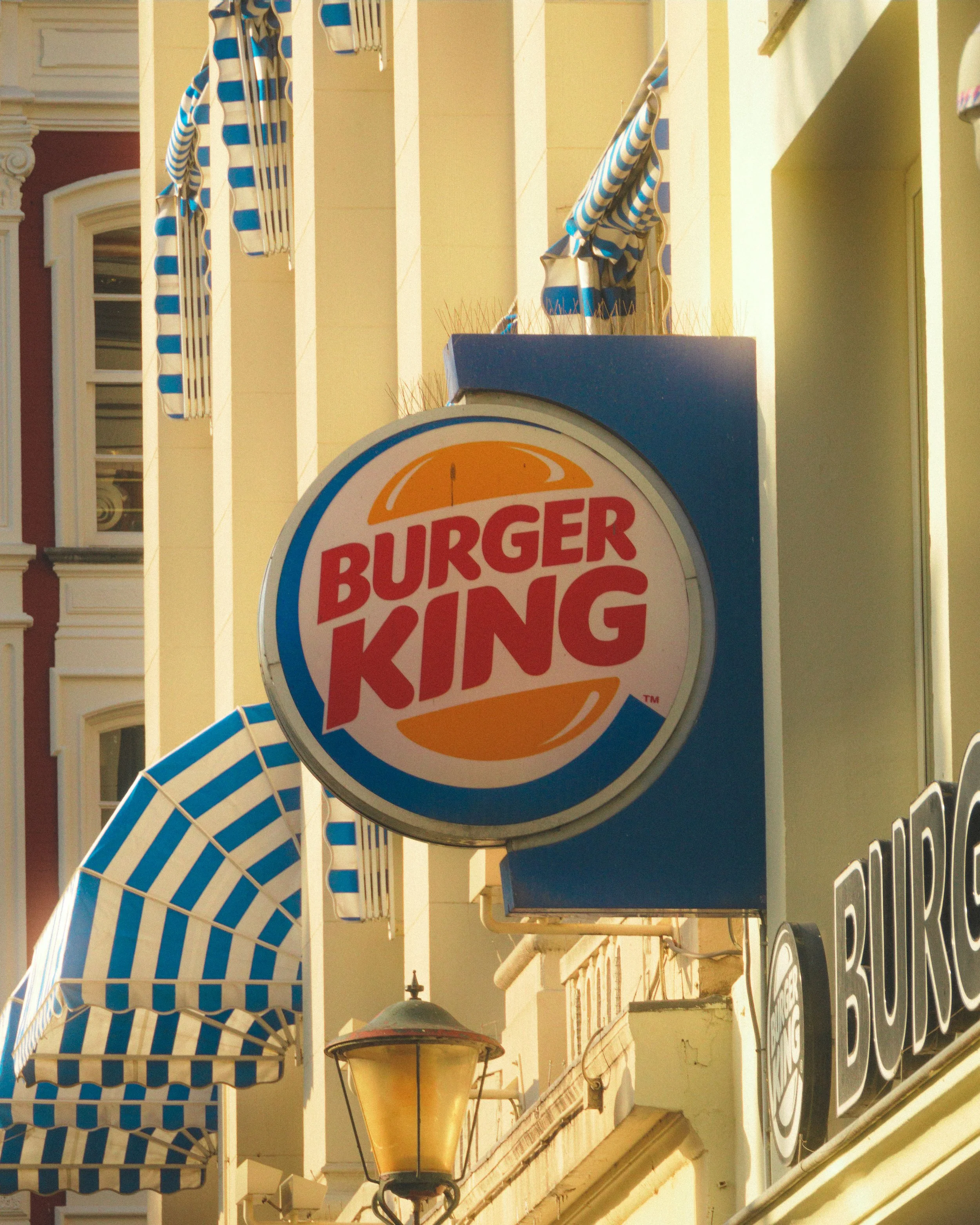 Burger-King-Logo an der Fassade eines gelben Gebäudes mit gestreifter Markise