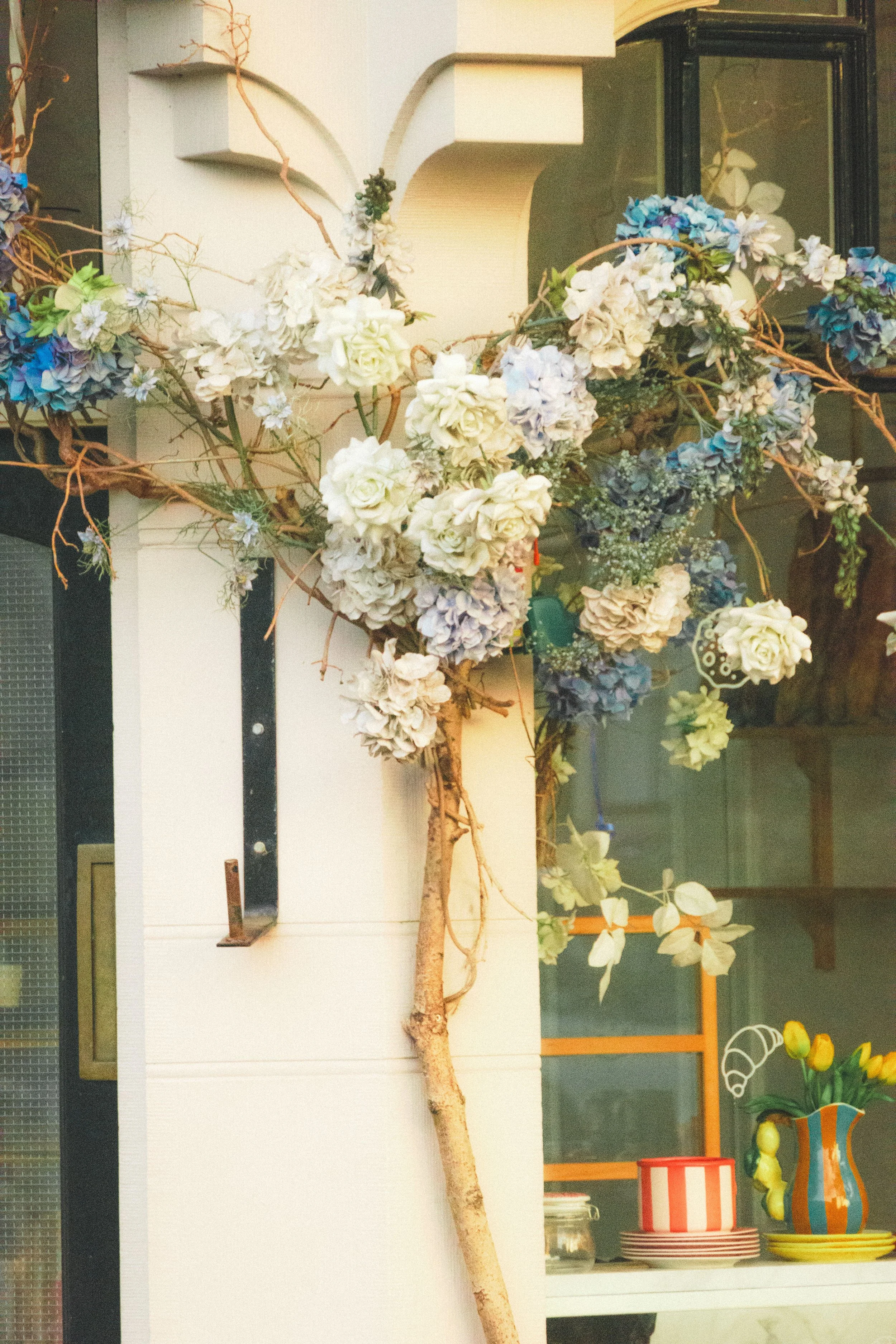 Weißer Blumenschmuck an einer Hauswand neben einer dunklen Tür