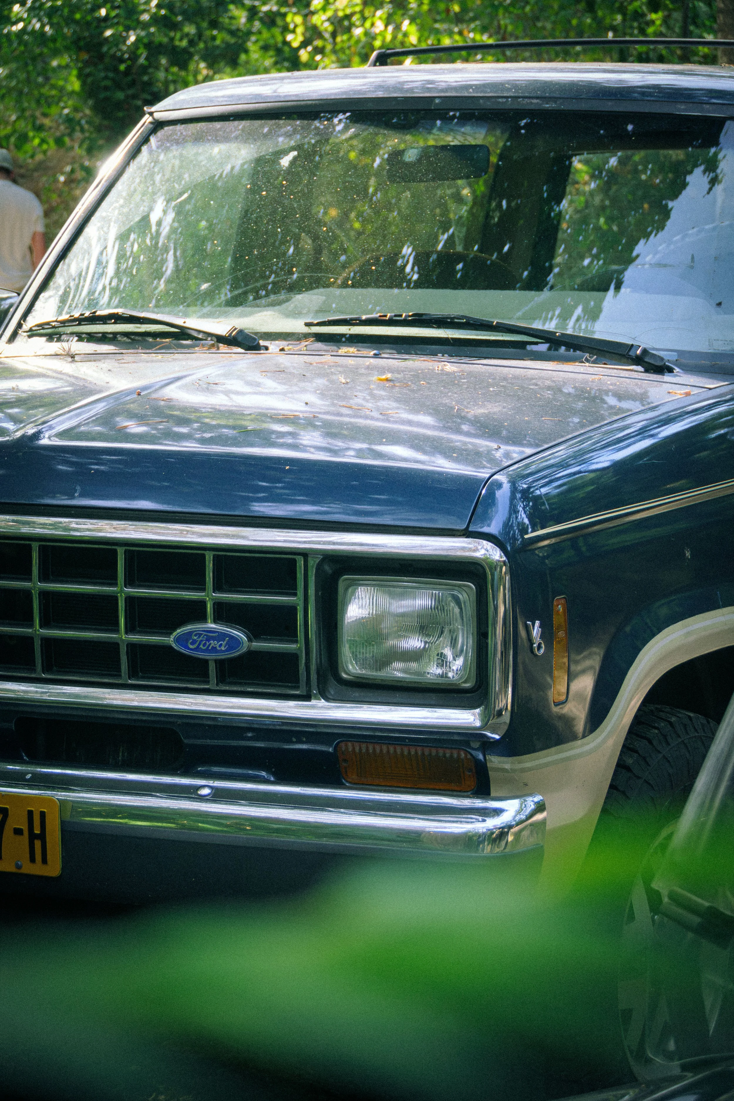Frontansicht eines dunkelblauen klassischen Pickup-Trucks unter grünen Bäumen