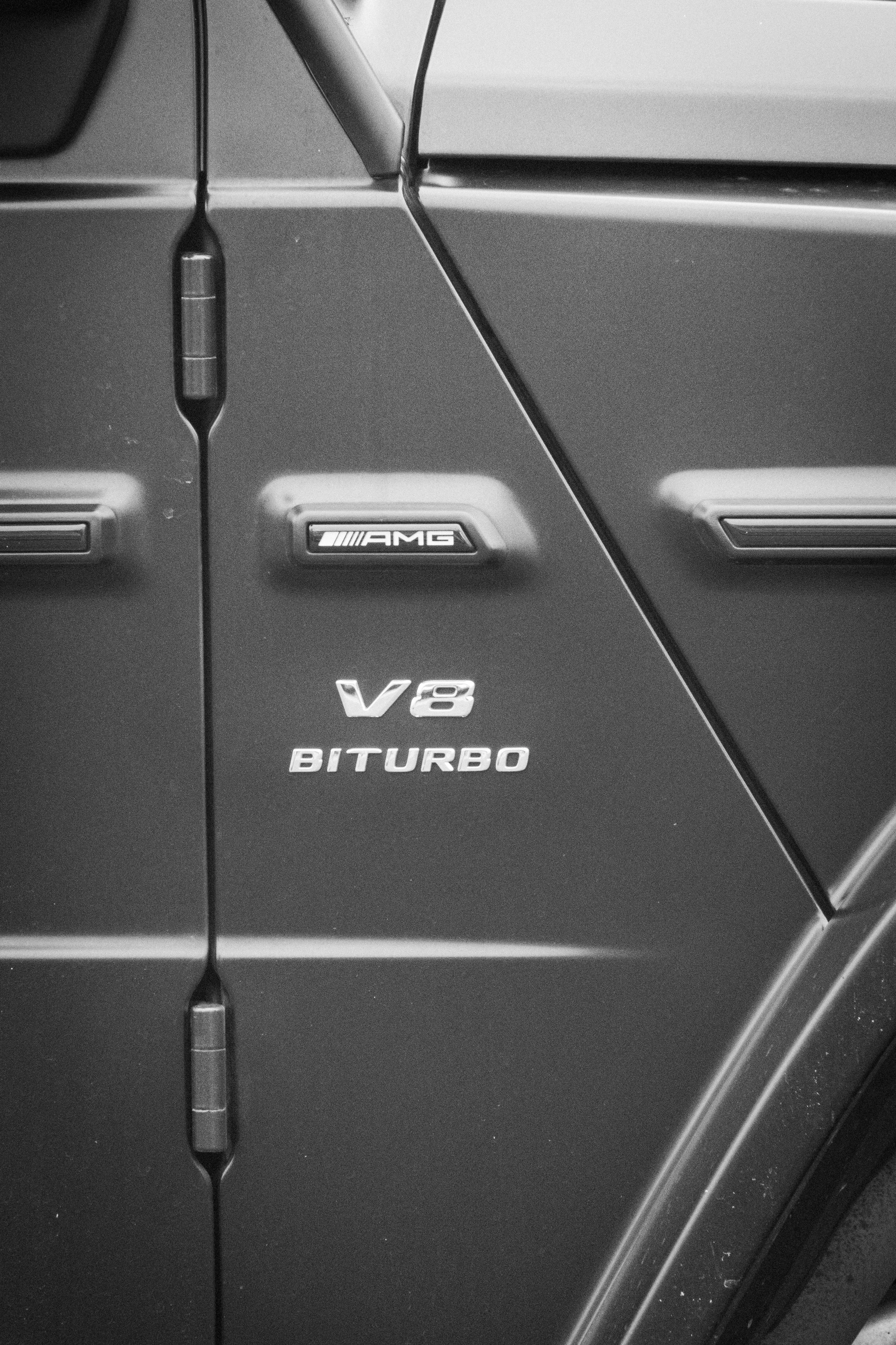 Schwarz-weiße Nahaufnahme des "V6 Biturbo"-Schriftzugs an der Fahrzeugflanke eines Sportwagens