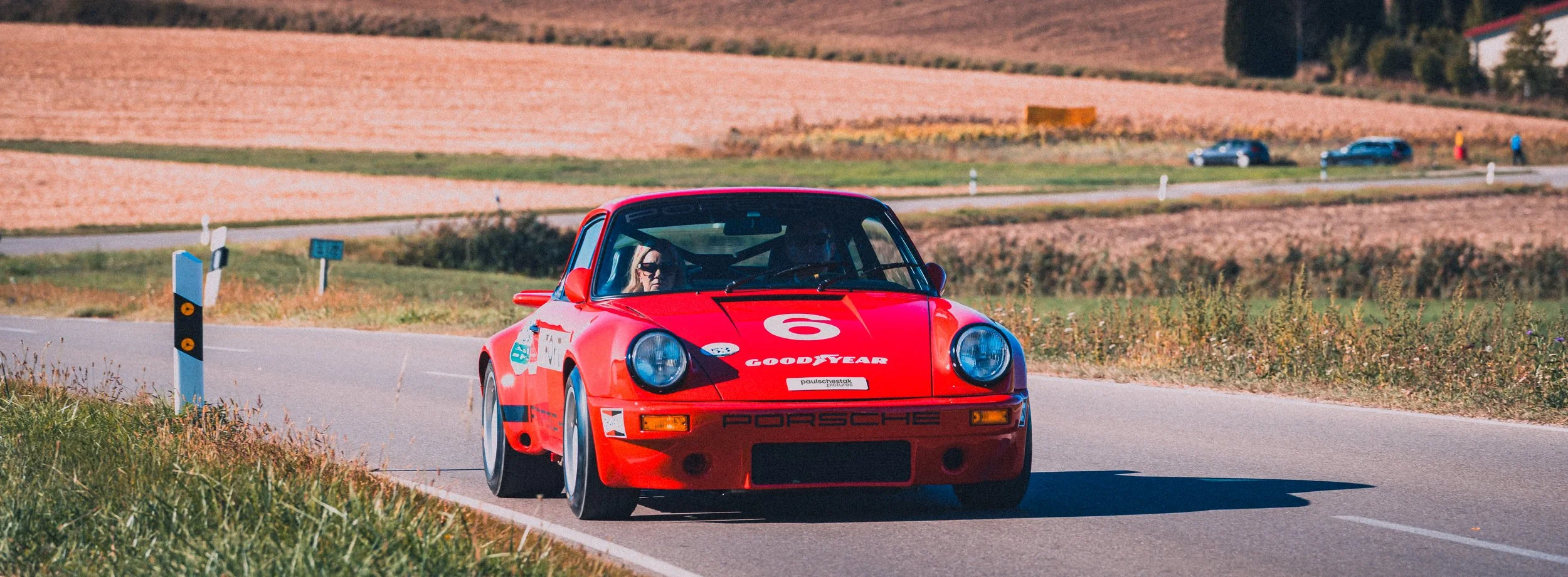 Roter Porsche 911 mit Startnummer auf einer Landstraße bei der Oldtimer-Rallye Fuggerstadt Classic