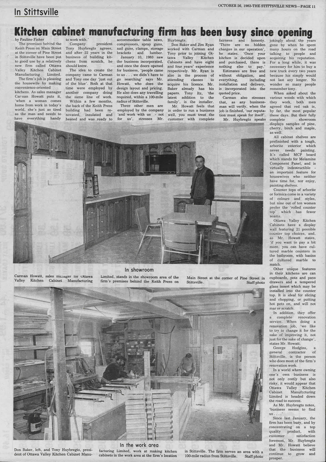 Black and white newspaper article titled 'Kitchen cabinet manufacturing firm has been busy since opening,' dated October 26, 1983. Includes two photos with captions: one showing Carman Howatt standing in a showroom with kitchen cabinets and furniture, and another of a woodworking workshop with workers making kitchen cabinets. The article discusses the company's history, products, and work process.