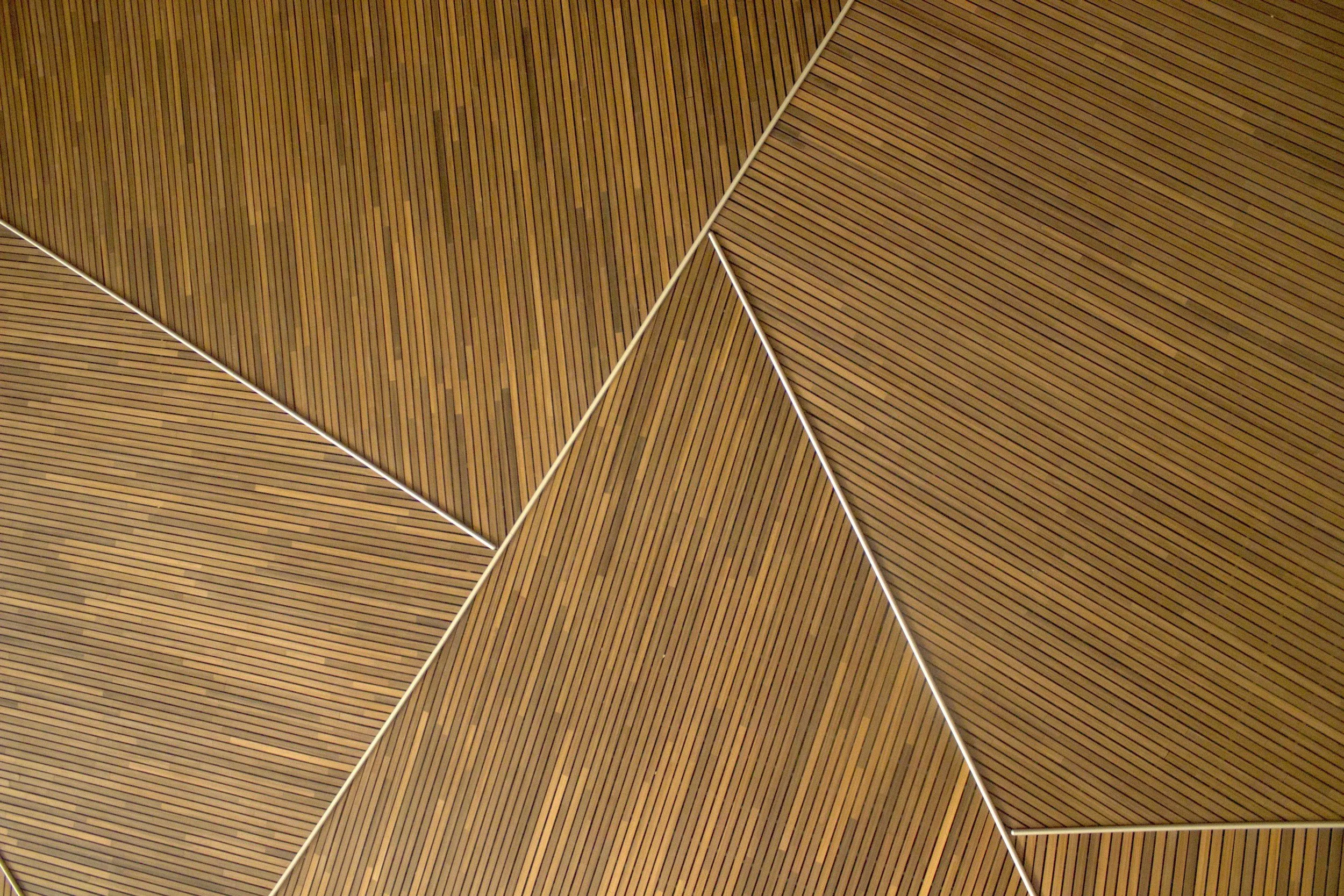 Close-up view of a wooden ceiling with geometric panels separated by white lines.