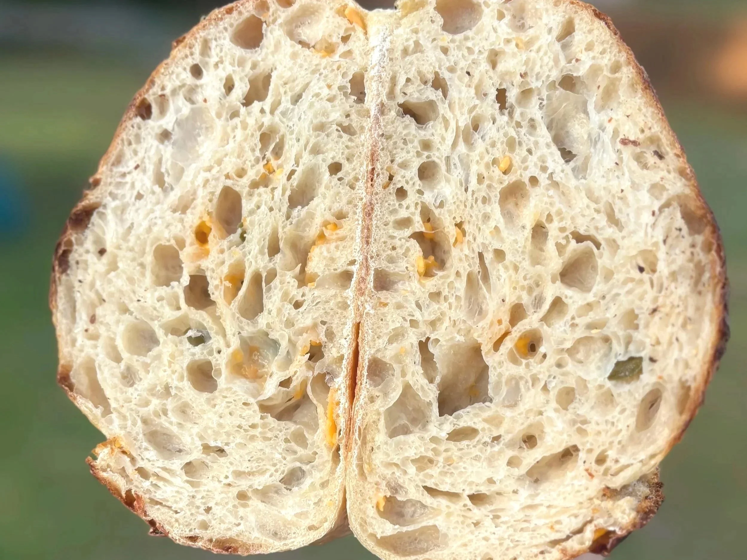 A close-up of a sliced loaf of bread showing its airy, hole-filled interior with a golden-brown crust.