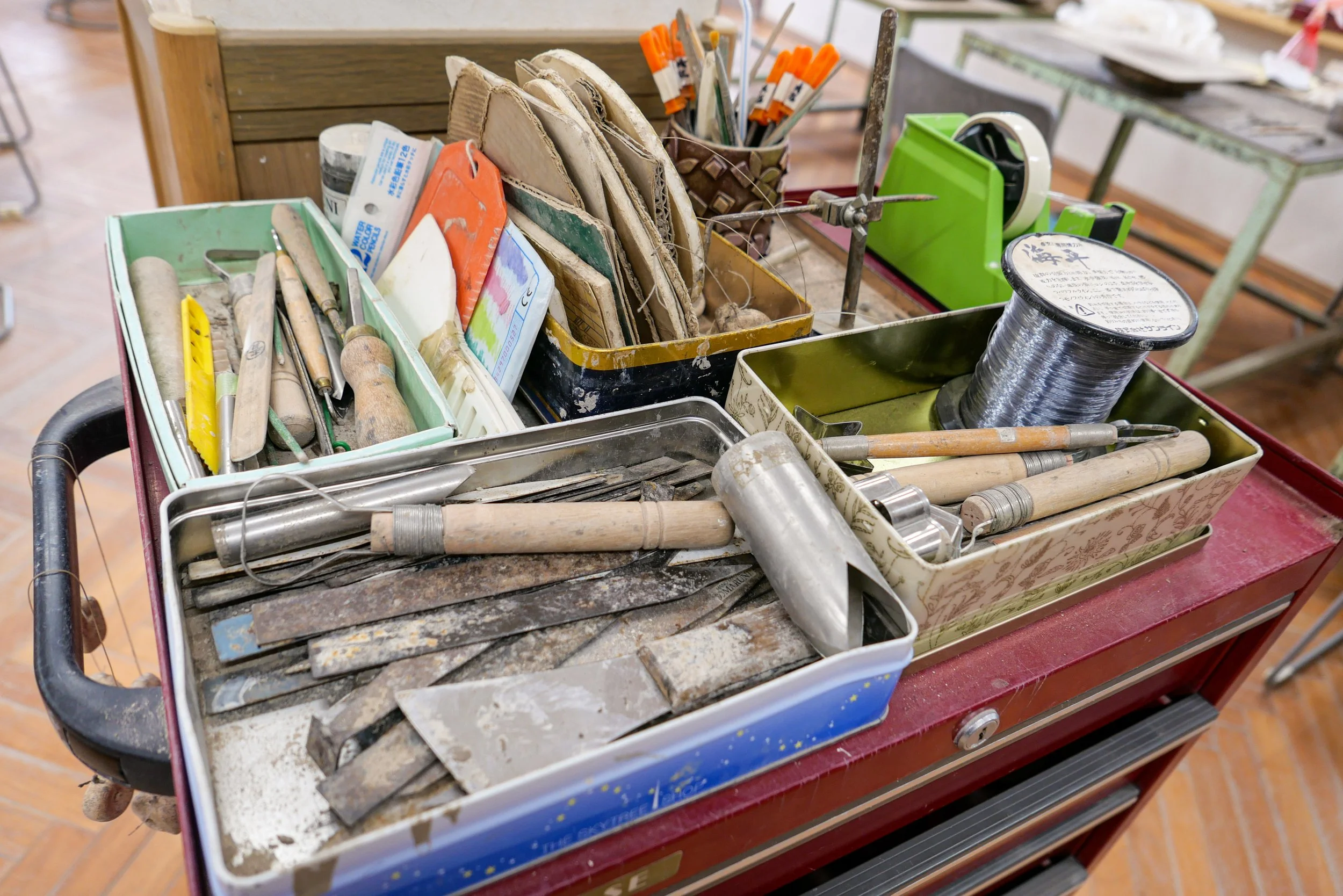 a close-up of a trolley holding well-used pottery tools at shigaraki seinenryo. blades, shapers, wire cutters, and brushes